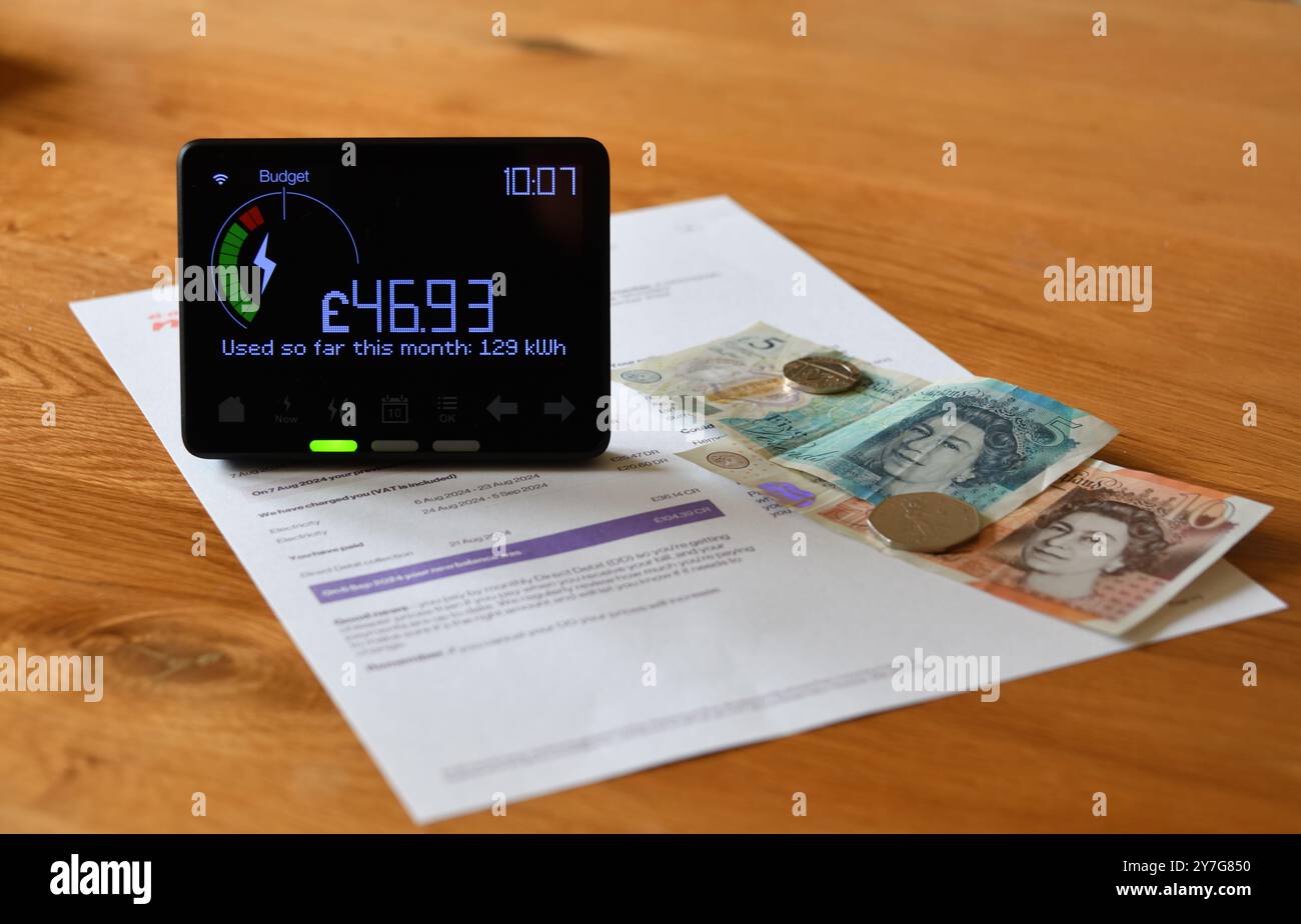 Compteur intelligent d'électricité en affichage à la maison (IHD) sur la table en bois montrant le coût mensuel et l'utilisation en kilowattheures (kWh) Banque D'Images