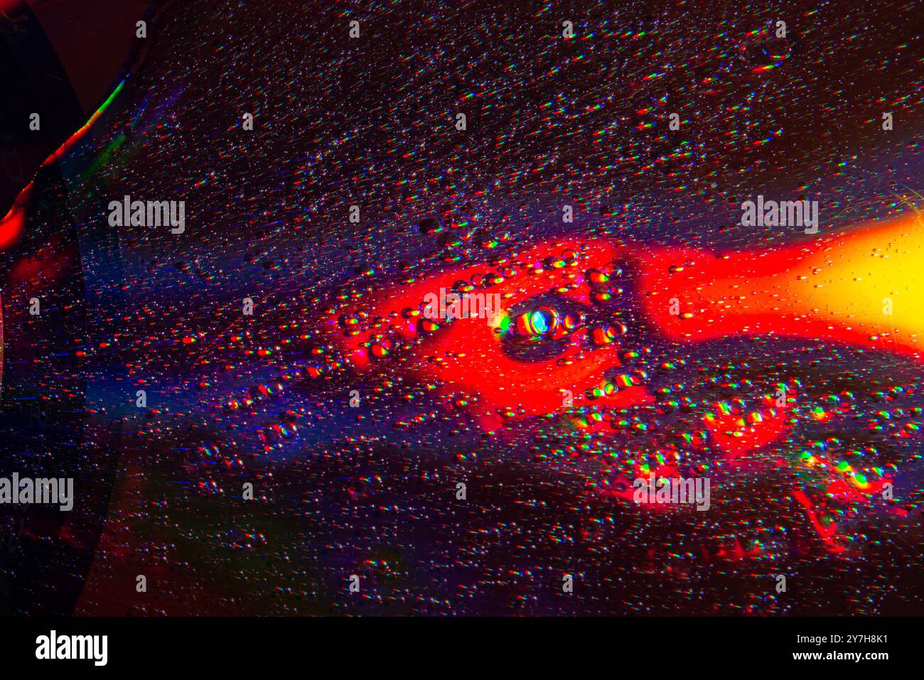 Une photo macro montrant des motifs et des couleurs de gouttes d'huile flottant sur une eau. Banque D'Images