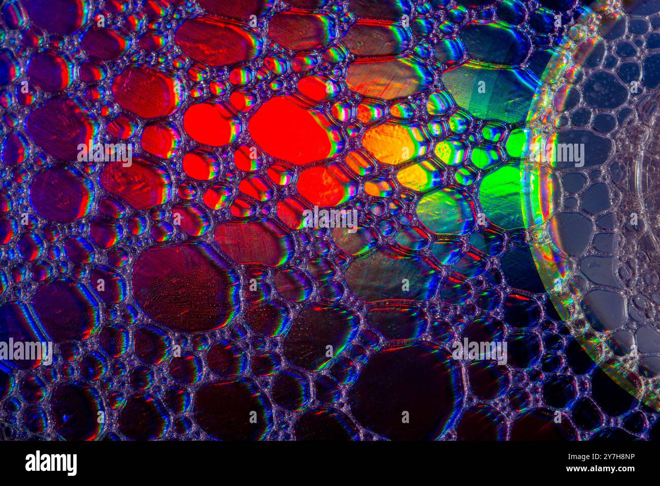 Une photo macro montrant des motifs et des couleurs de gouttes d'huile flottant sur une eau. Banque D'Images