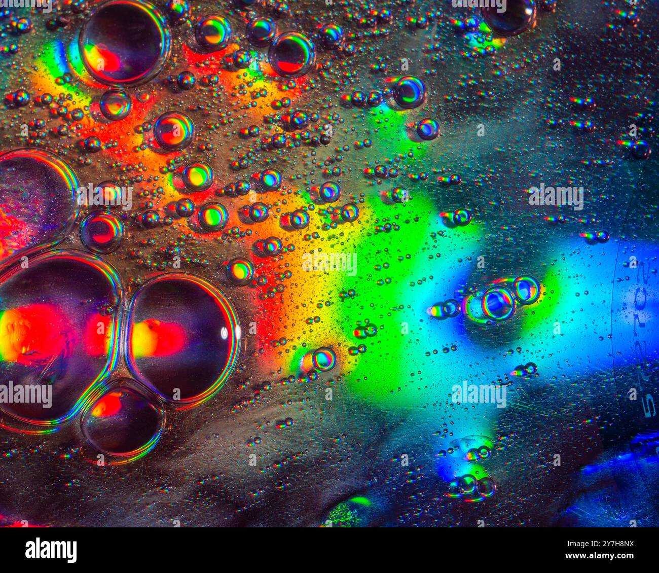 Une photo macro montrant des motifs et des couleurs de gouttes d'huile flottant sur une eau. Banque D'Images