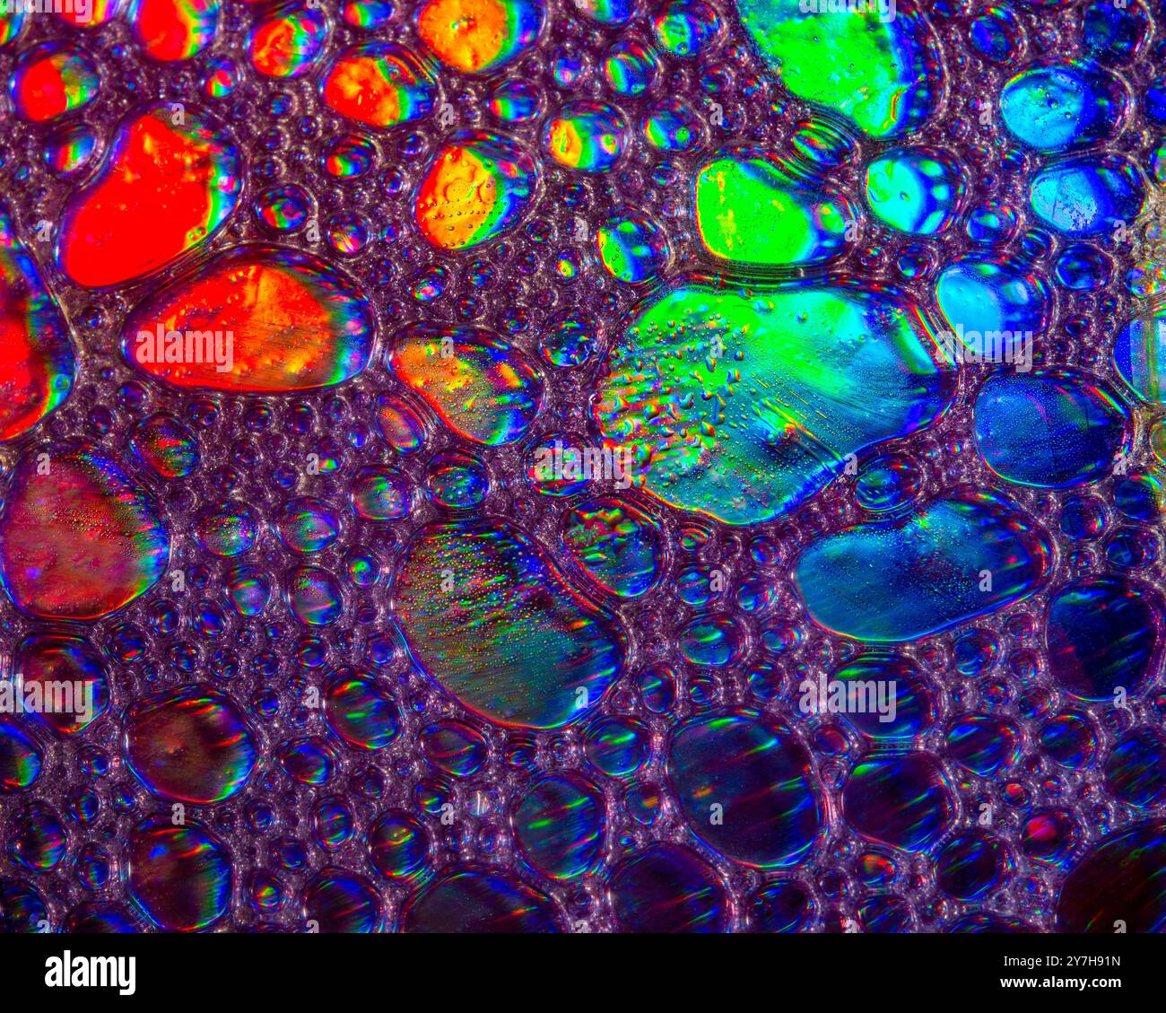 Une photo macro montrant des motifs et des couleurs de gouttes d'huile flottant sur une eau. Banque D'Images