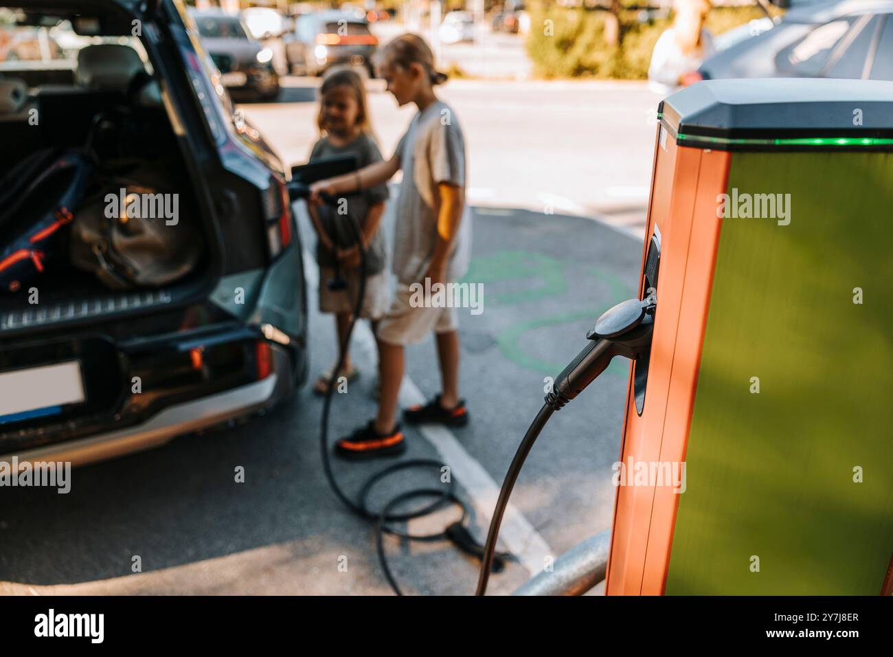 Électricité passant par la prise branchée dans le kiosque à la station de charge du véhicule Banque D'Images