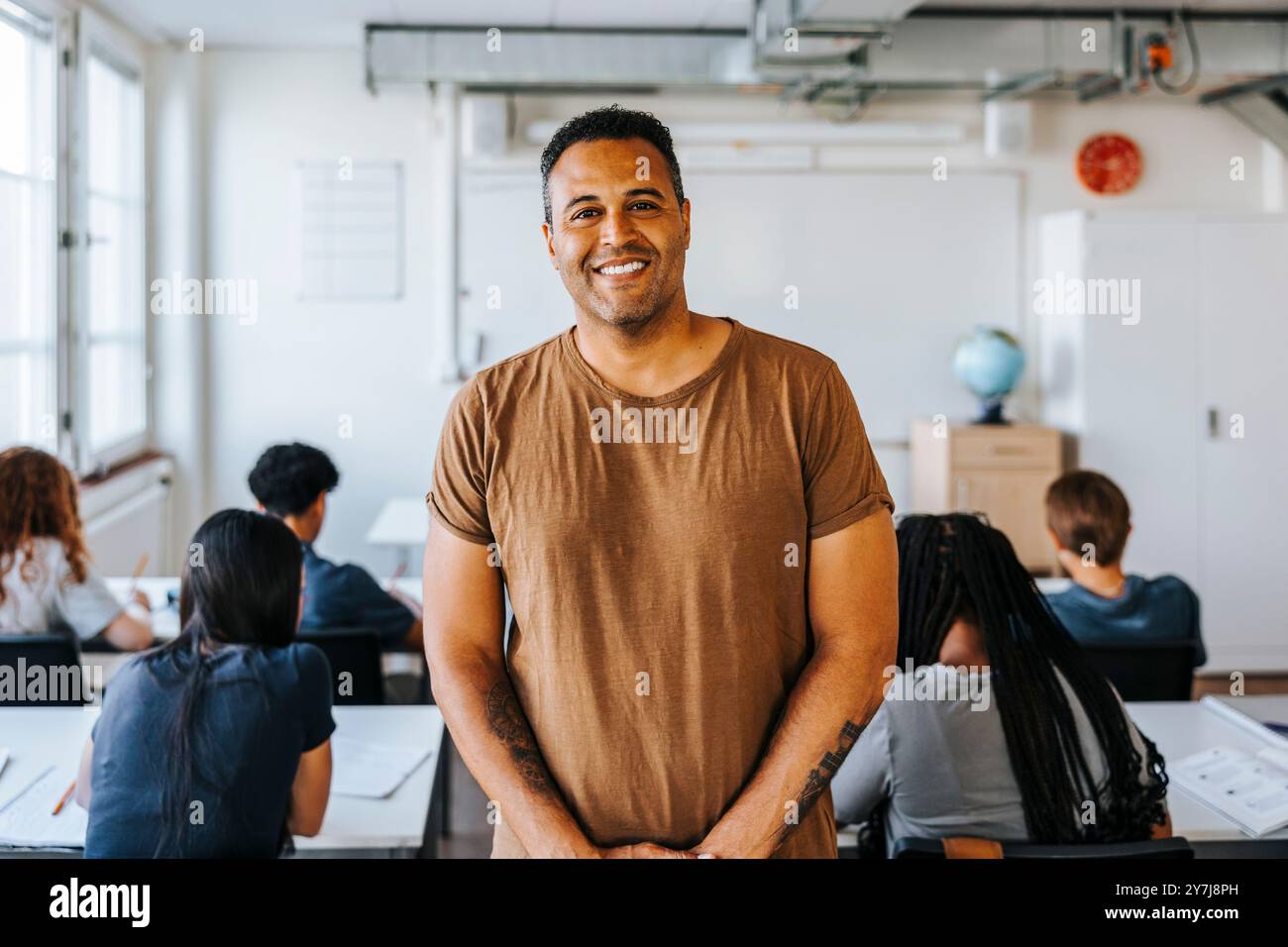 Portrait d'un professeur masculin souriant debout dans une salle de classe au collège Banque D'Images