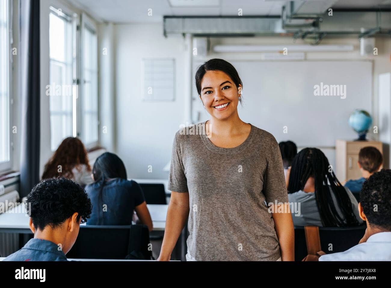 Portrait d'une enseignante heureuse debout dans une salle de classe au collège Banque D'Images