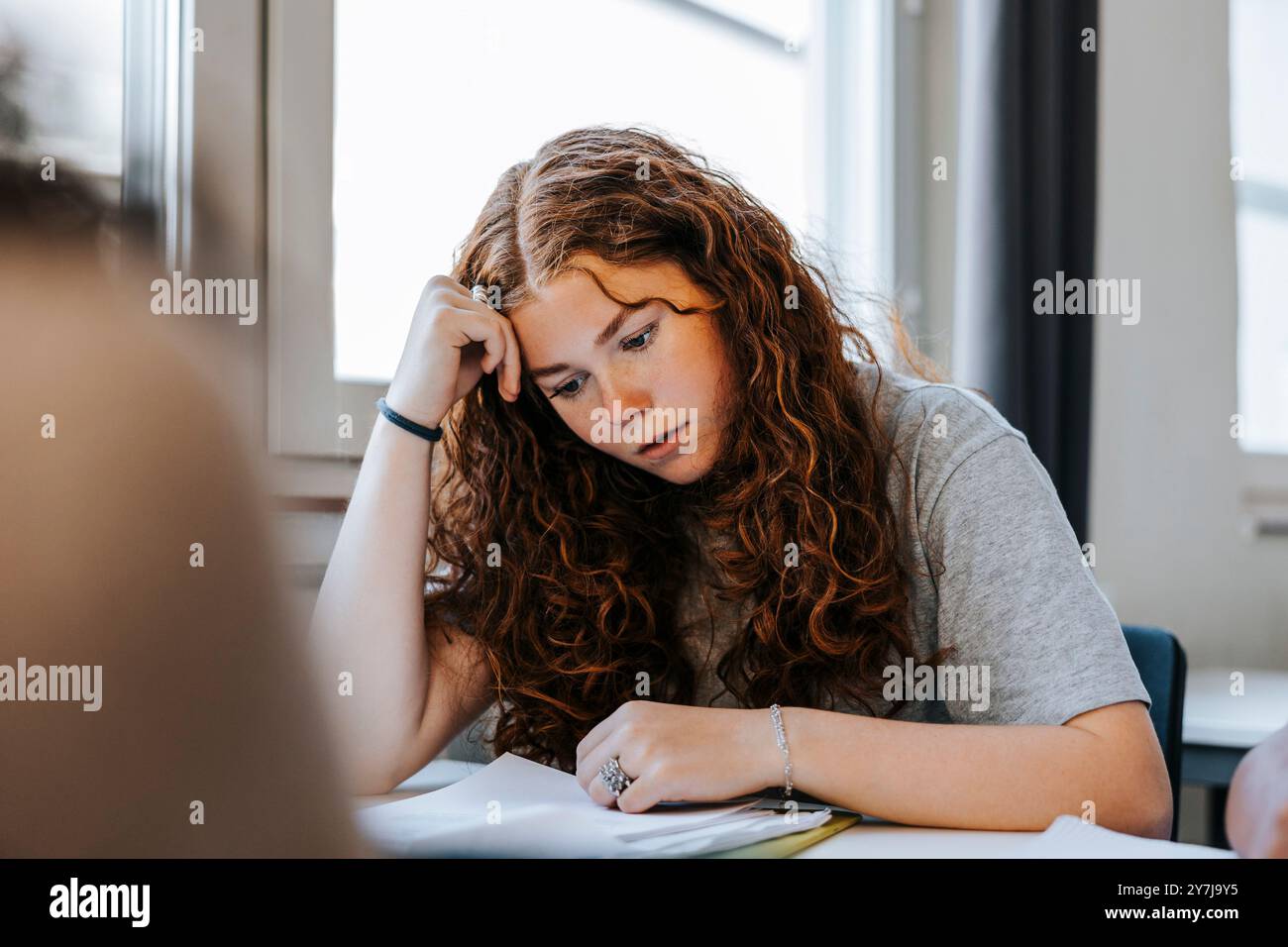 Adolescent stressé aux cheveux frisés étudiant en classe au collège Banque D'Images