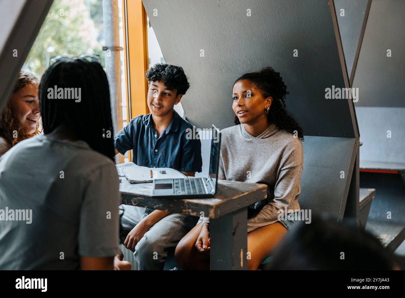 Groupe d'étudiants multiraciaux étudiant à travers un ordinateur portable dans la cafétéria au collège Banque D'Images