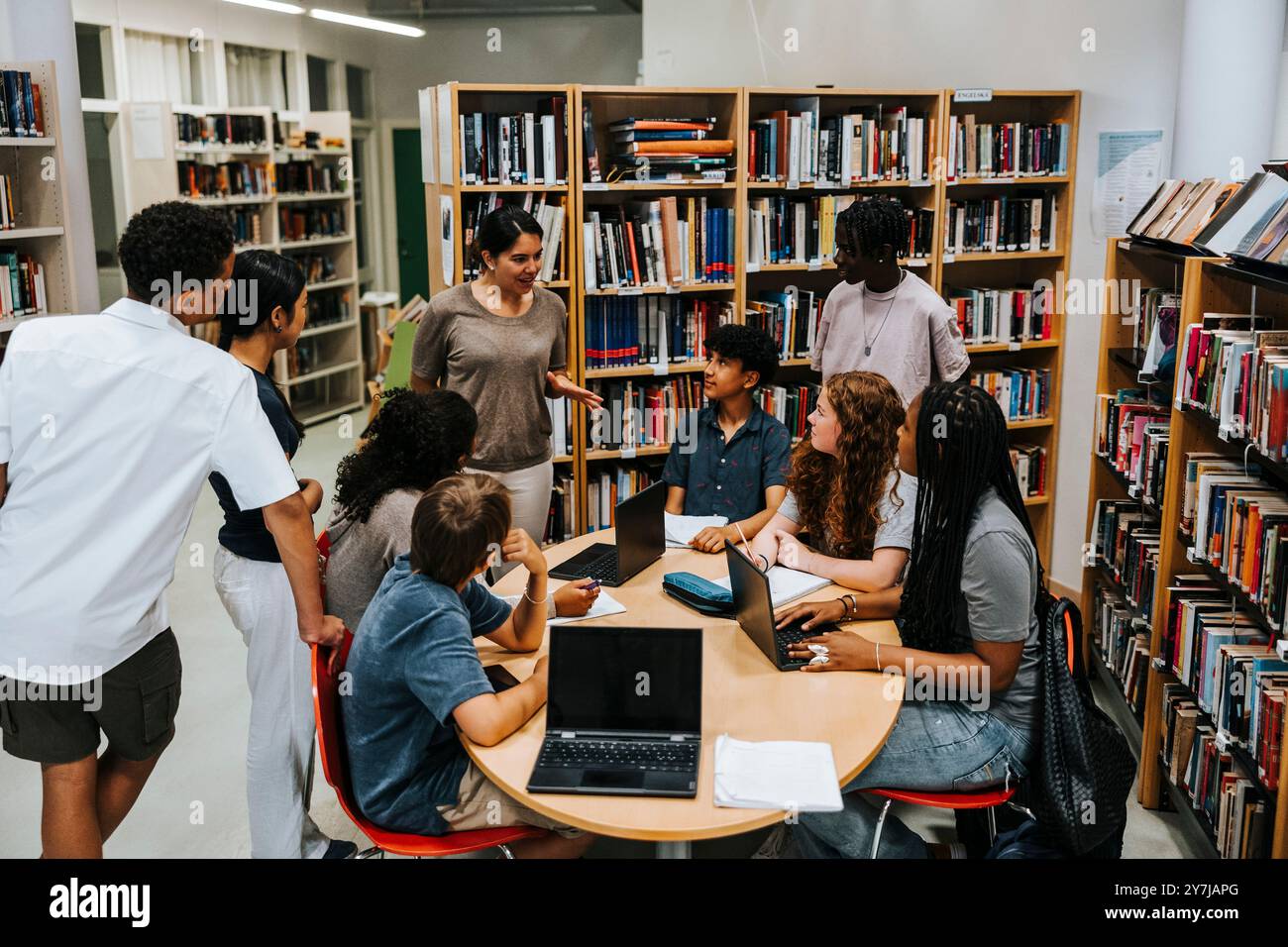 Vue en angle élevé du professeur féminin enseignant le groupe d'étudiants masculins et féminins dans la bibliothèque au collège secondaire Banque D'Images