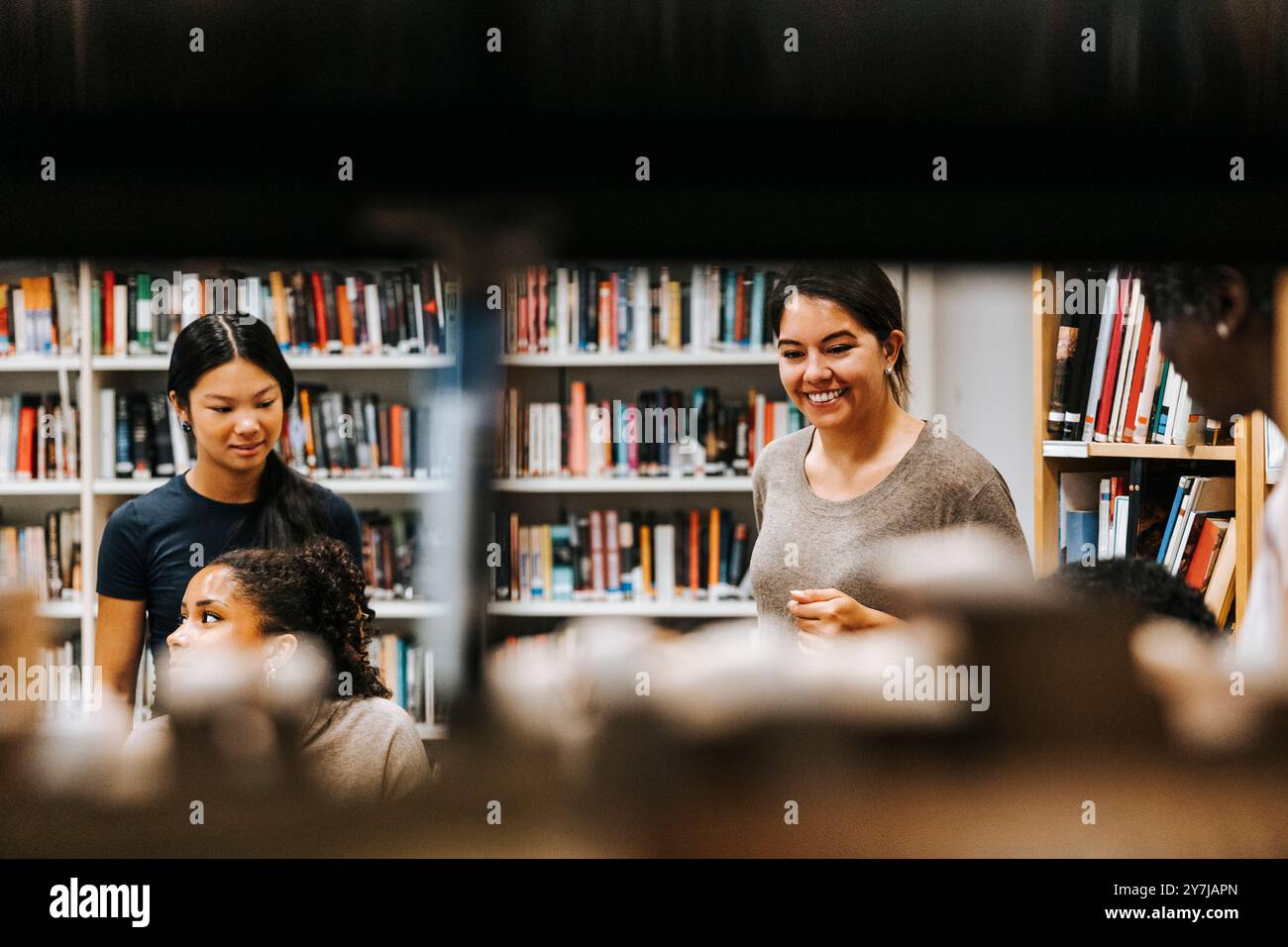 Heureuse bibliothécaire avec des étudiants à la bibliothèque à l'école Banque D'Images