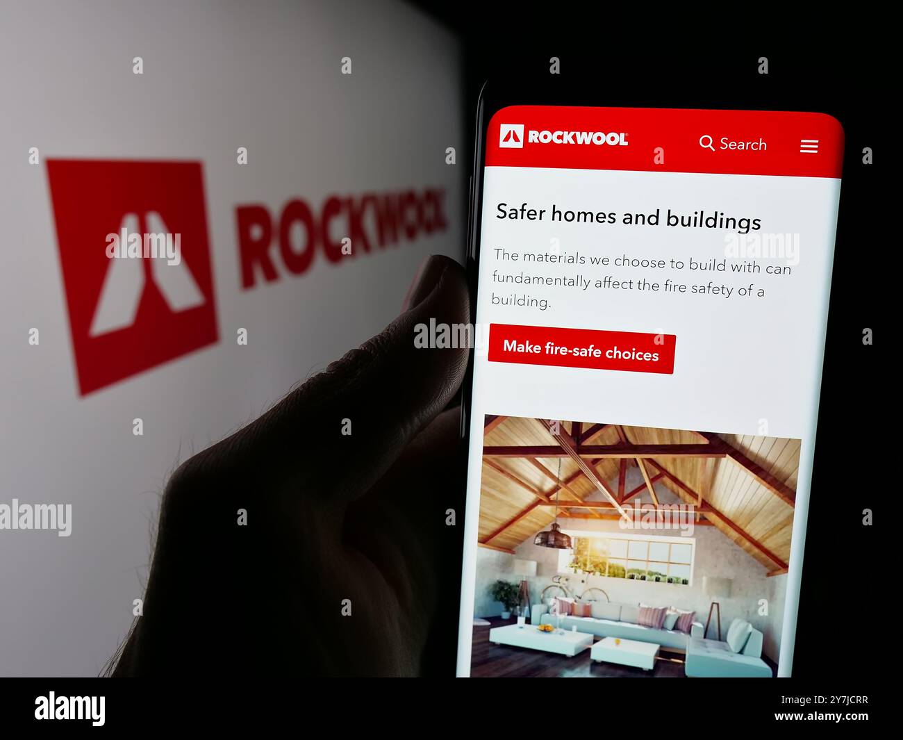 Personne tenant le téléphone portable avec la page Web de la société danoise de laine minérale Rockwool COMME sur l'écran devant le logo. Concentrez-vous sur le centre de l'écran du téléphone. Banque D'Images