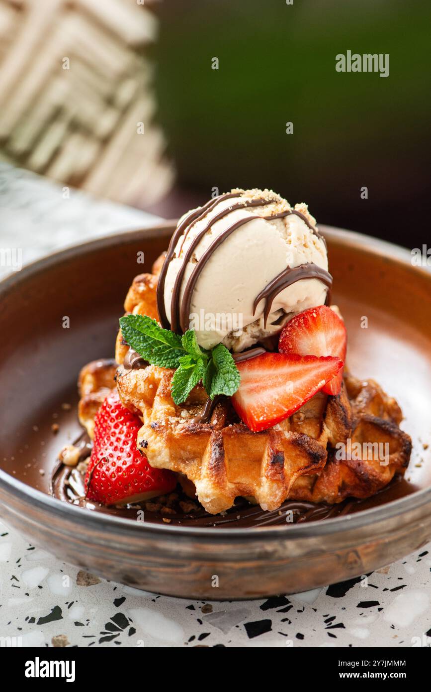 Gaufres américaines avec crème glacée, fraises, sirop d'érable et pépites de chocolat noir. Banque D'Images