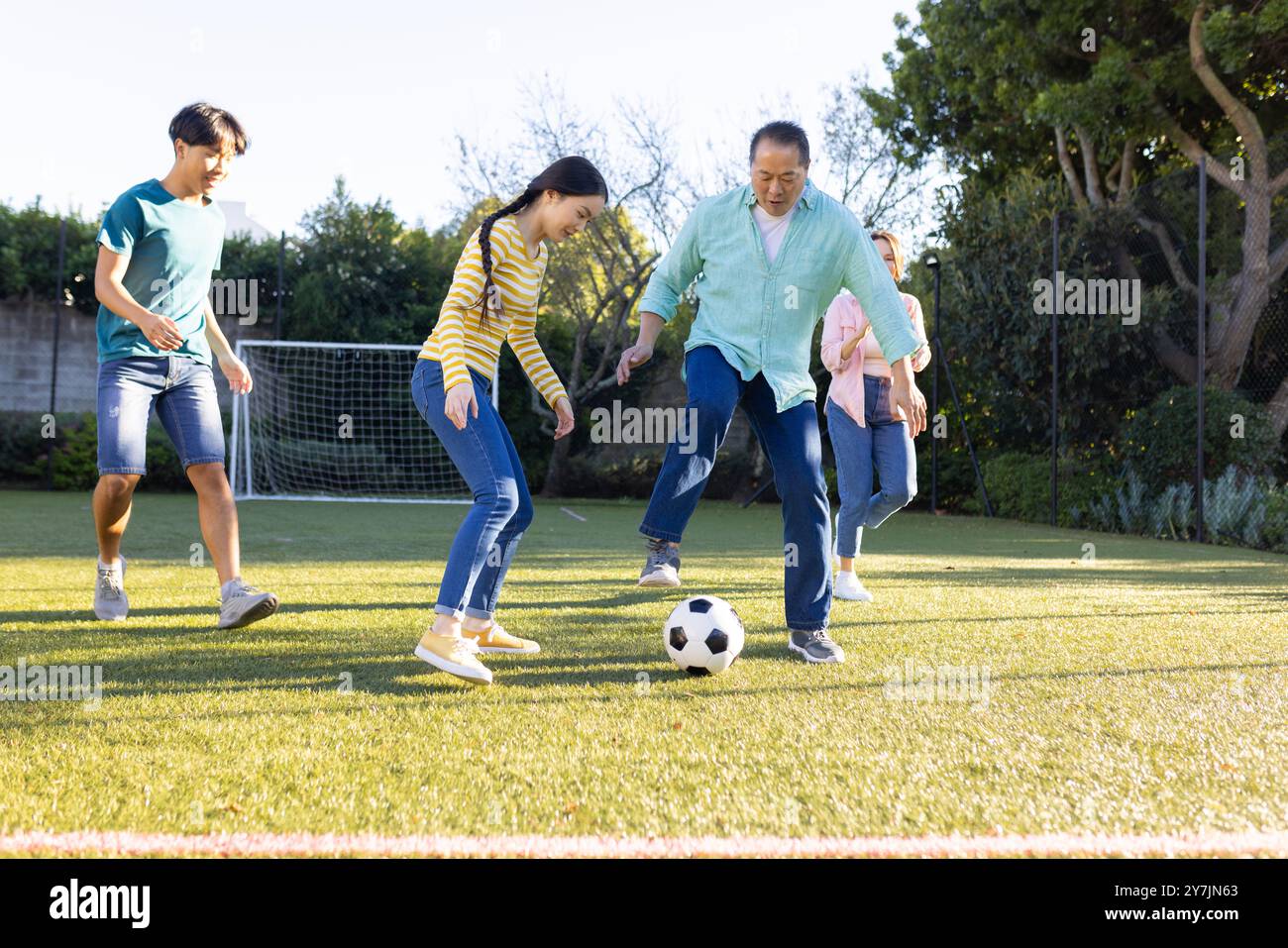 Jouer au football sur le terrain en herbe, famille profitant de l'activité de plein air ensemble Banque D'Images