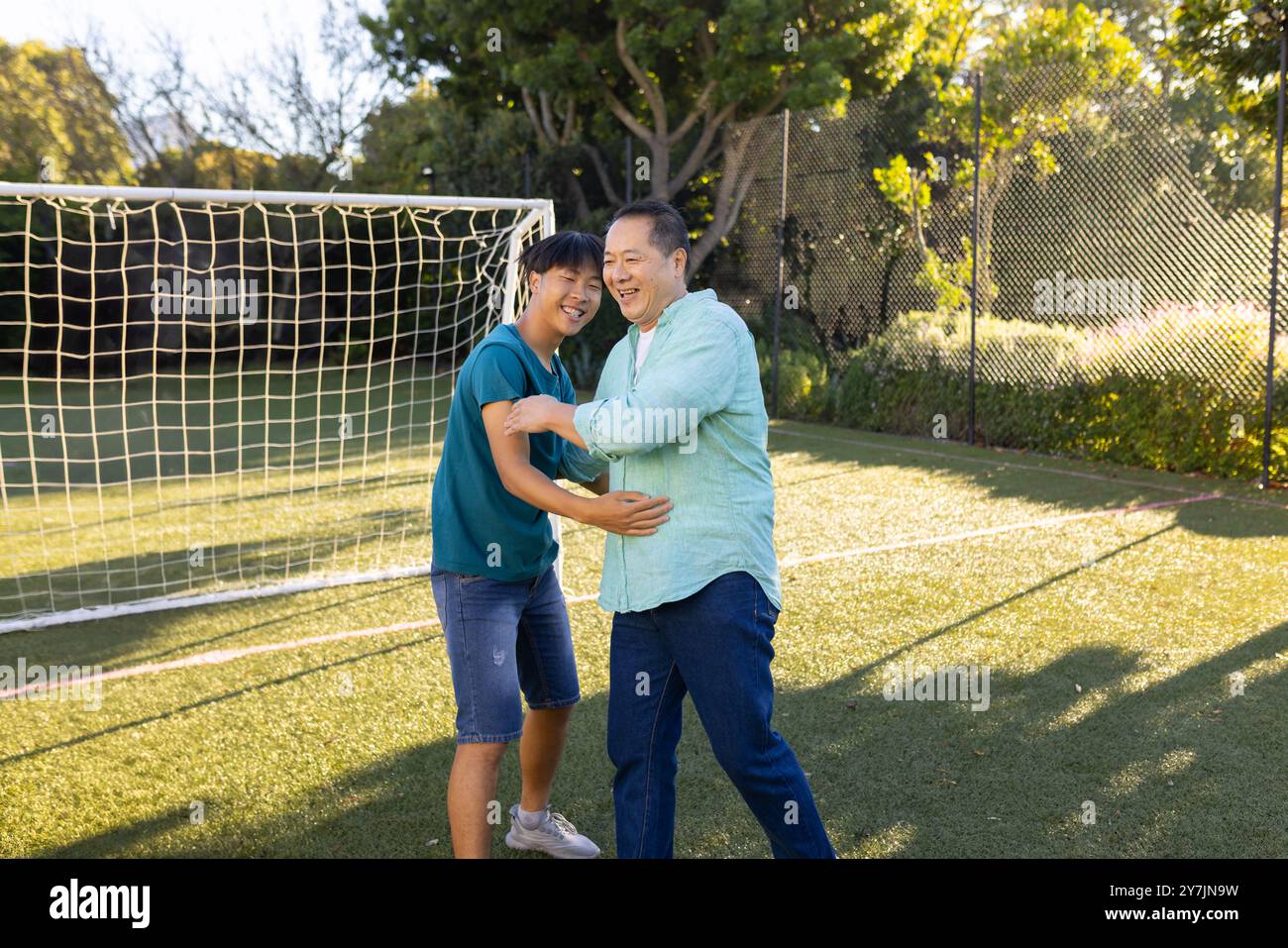 père asiatique et fils jouant ensemble sur le terrain de football, profitant du temps en plein air Banque D'Images