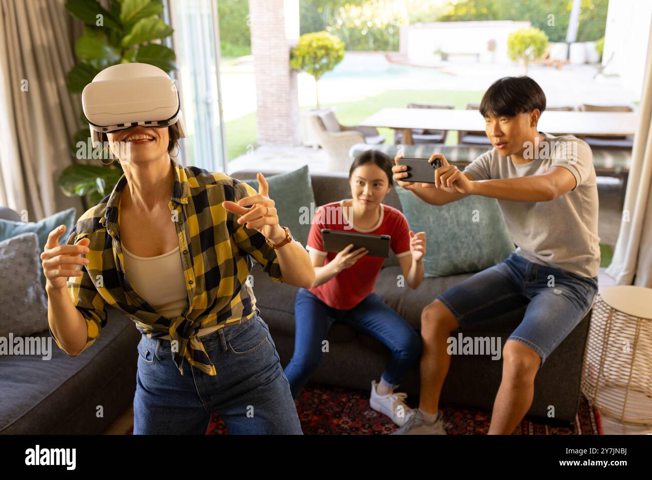 Jouer à un jeu de réalité virtuelle en utilisant un casque VR, mère avec des amis regardant et enregistrant Banque D'Images