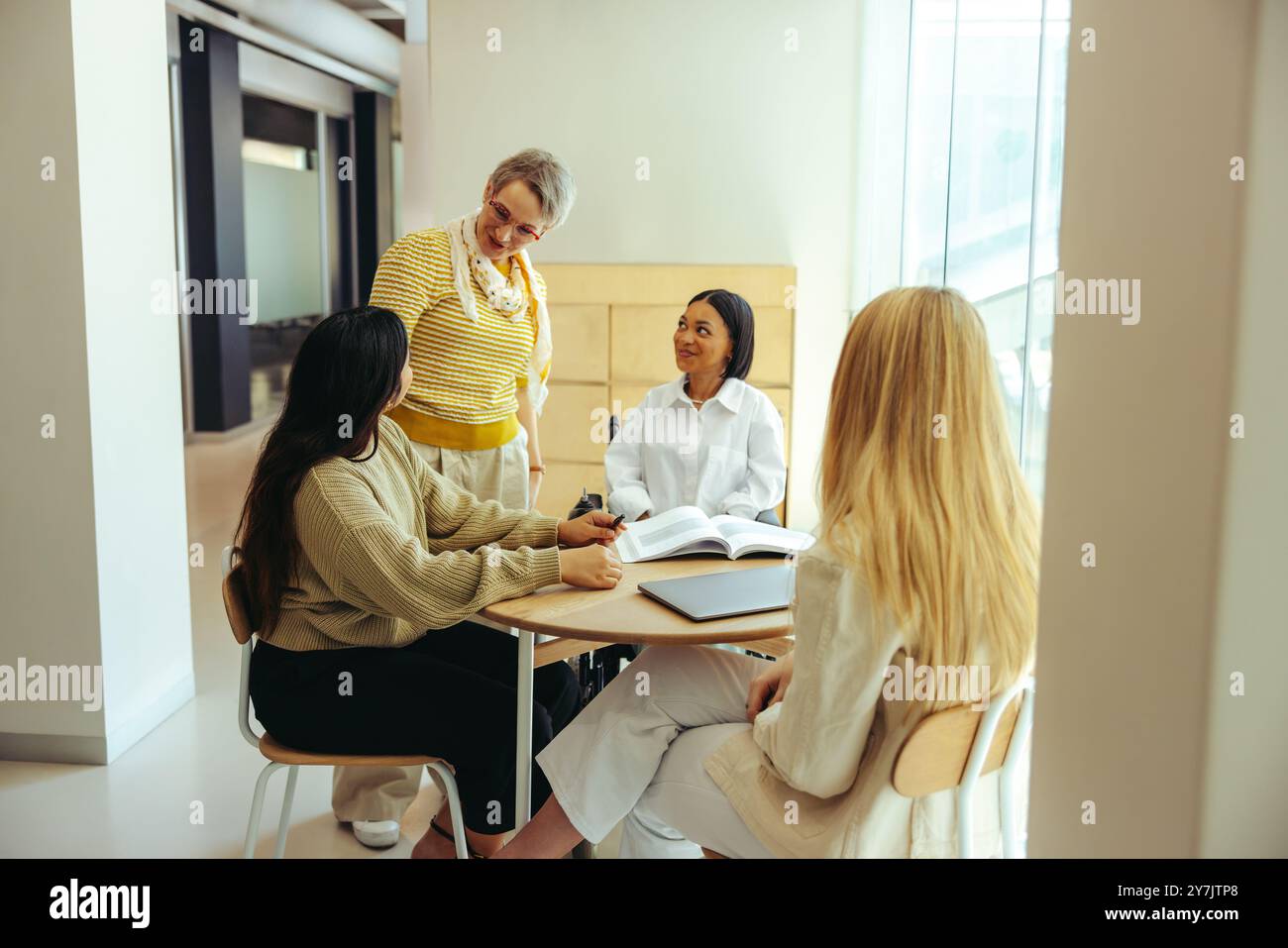 Groupe diversifié d'étudiants d'université étudiant ensemble dans une bibliothèque de campus de ville. Engagé dans la discussion et le travail d'équipe, améliorant l'expérience d'apprentissage. Banque D'Images