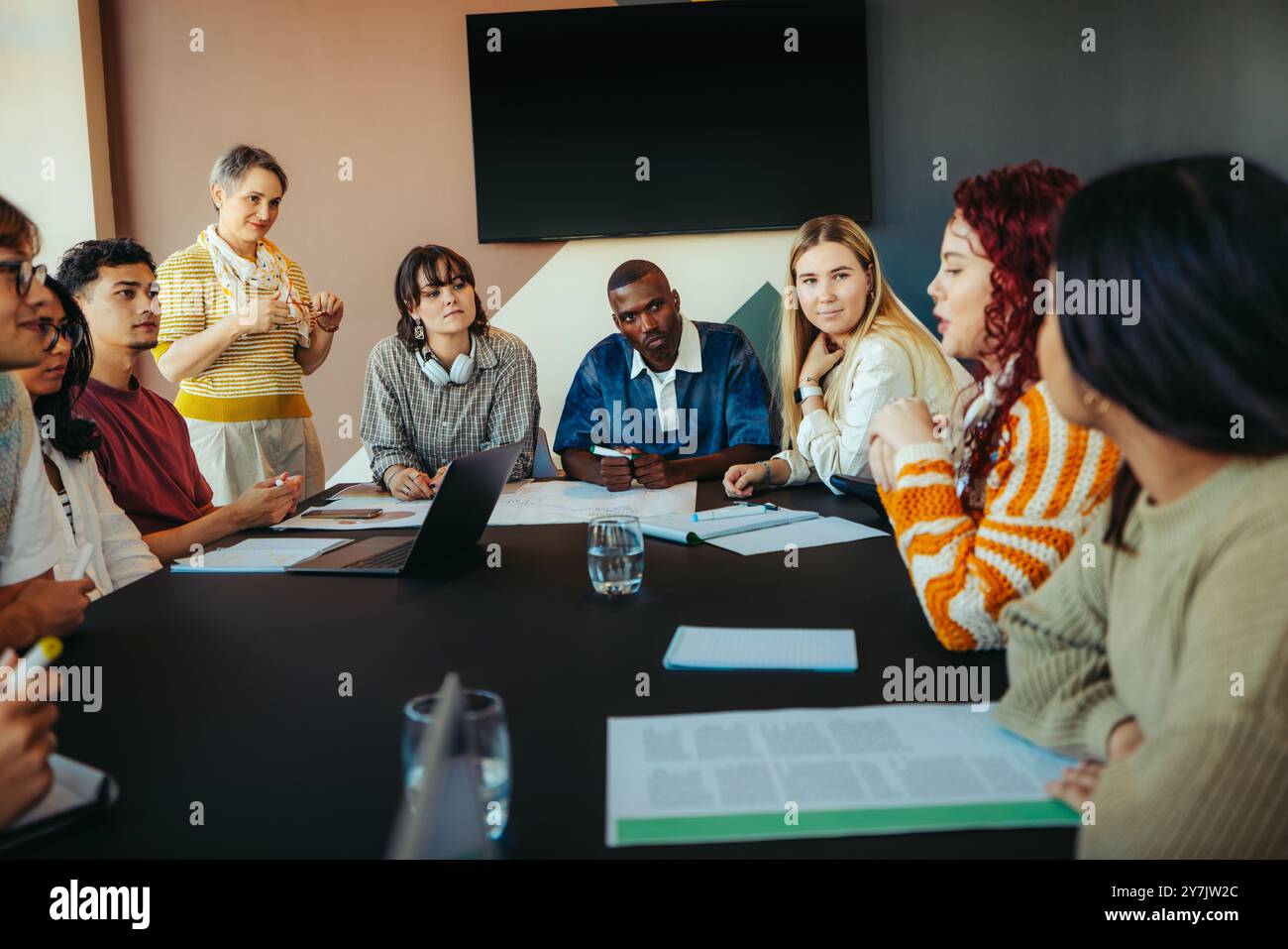 Groupe diversifié de camarades de classe participant activement à une discussion d'apprentissage autour d'une table, favorisant la collaboration et l'éducation dans un classroo moderne Banque D'Images