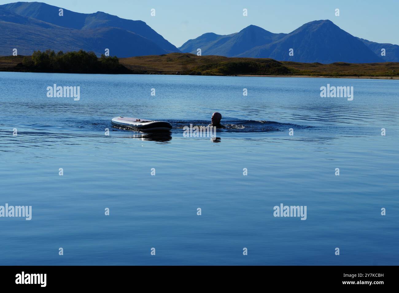 Homme apprenant à paddle board (SUPB) sur le Loch Laidon, avec en toile de fond les montagnes Glen Coe, Rannoch Moor, Écosse, Royaume-Uni Banque D'Images