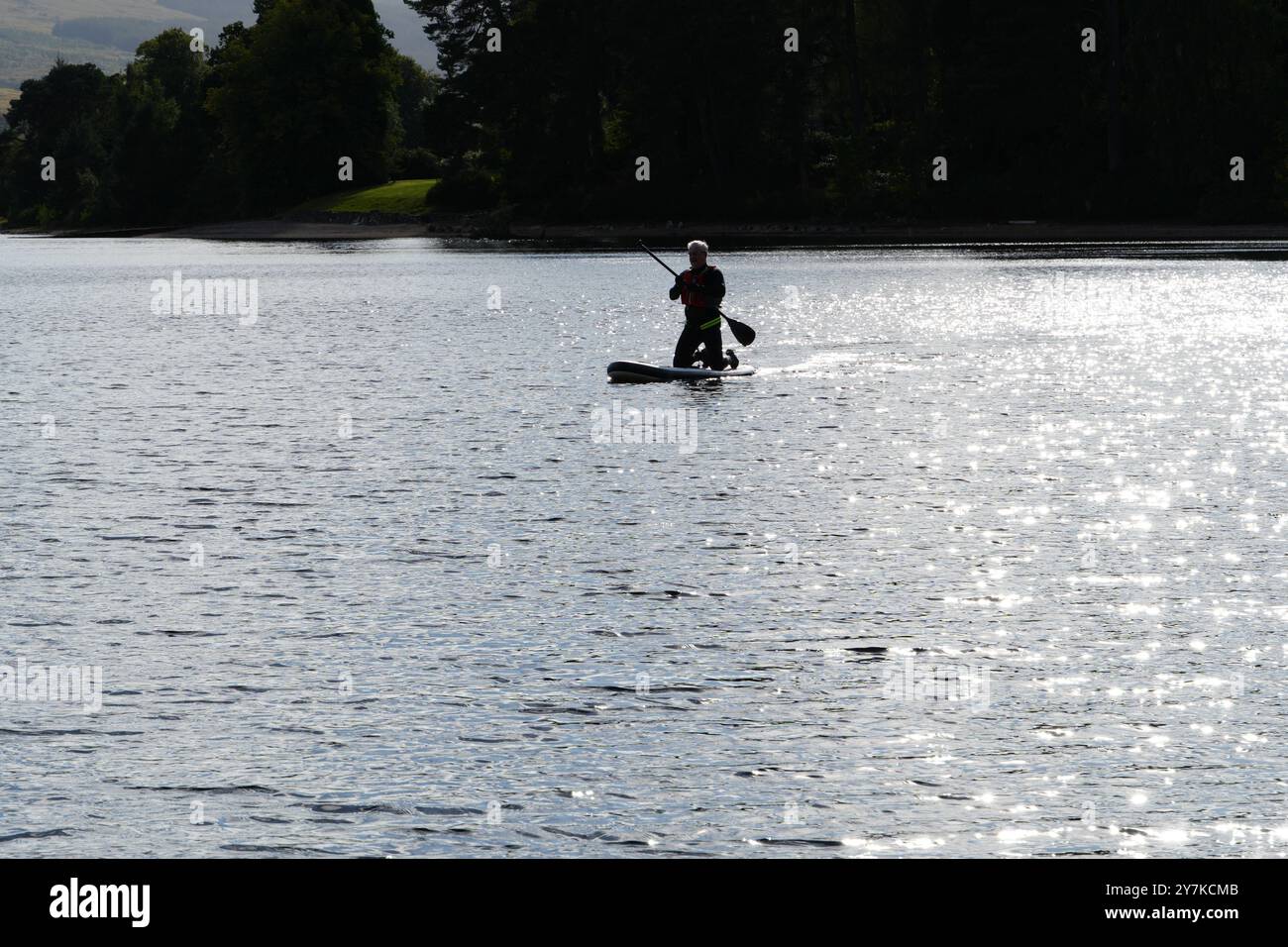 Homme apprenant à paddle board (SUPB) sur loch en Écosse, Royaume-Uni Banque D'Images