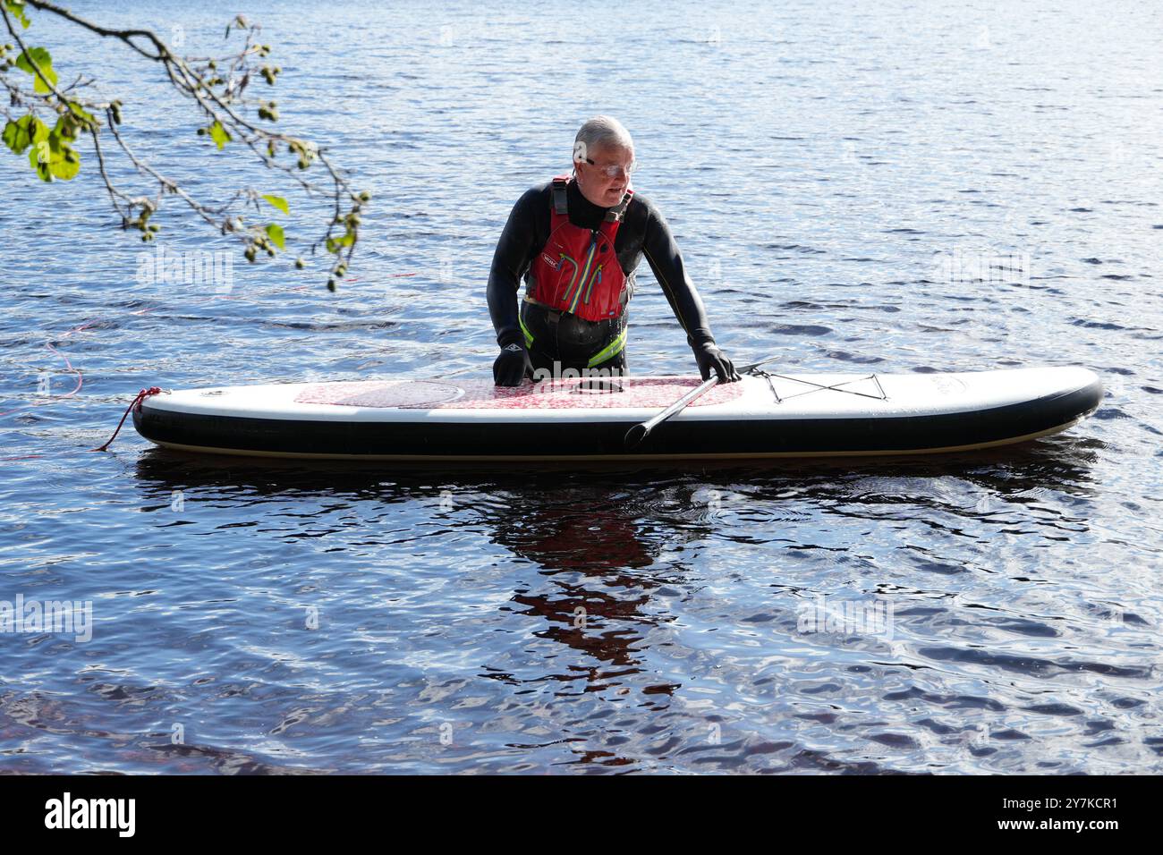 Homme apprenant à paddle board (SUPB) sur Loch Rannoch en Écosse, Royaume-Uni Banque D'Images