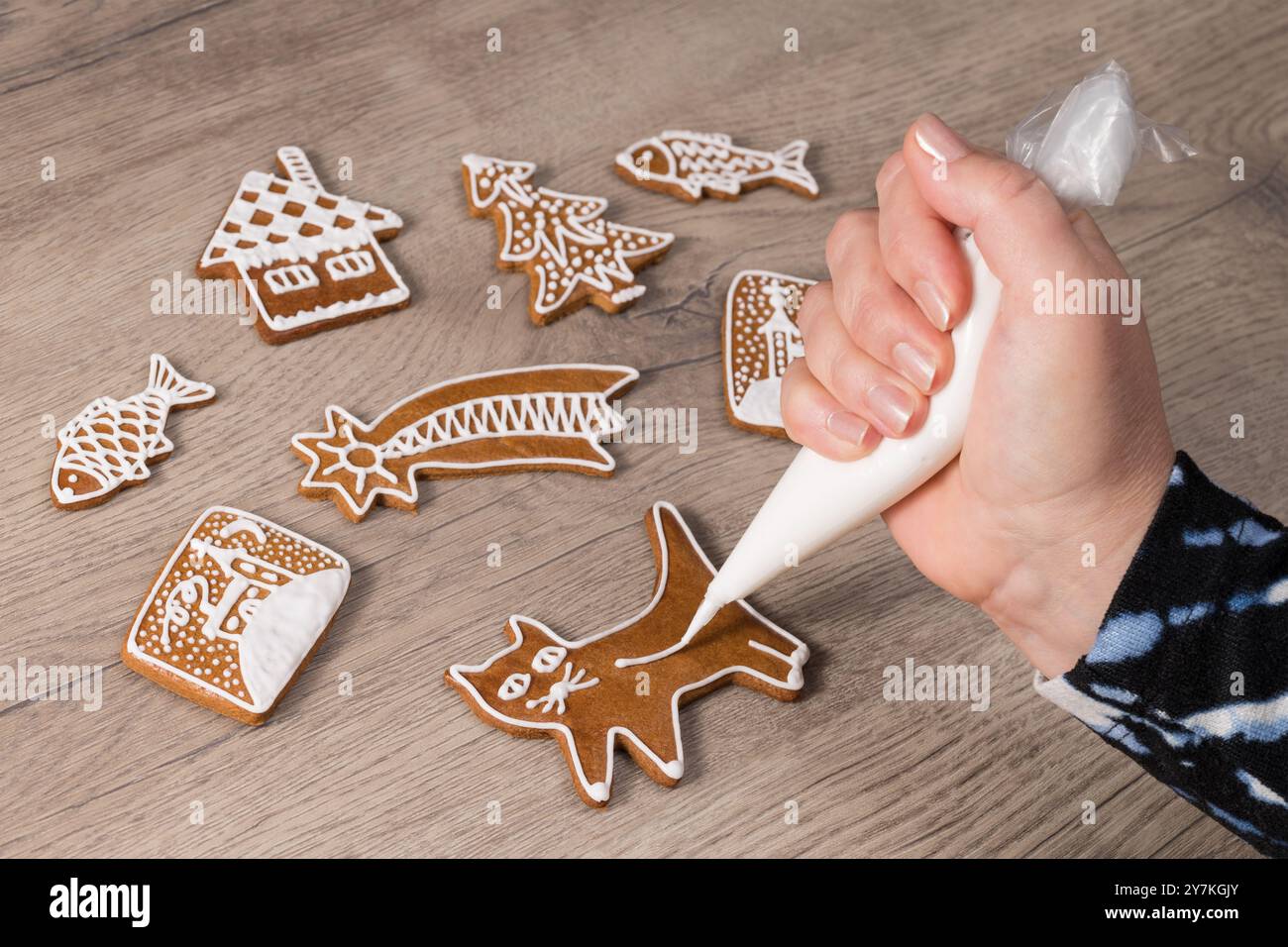 Gros plan d'une main humaine à décorer mignon chat de chaton de pain d'épices doux par sac à passepoil. Fabrication de décorations de Noël cuites à partir de pâtisseries aromatiques traditionnelles. Banque D'Images