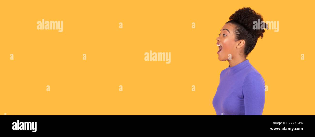Femme excitée exprimant la joie sur un fond jaune solide à l'intérieur Banque D'Images