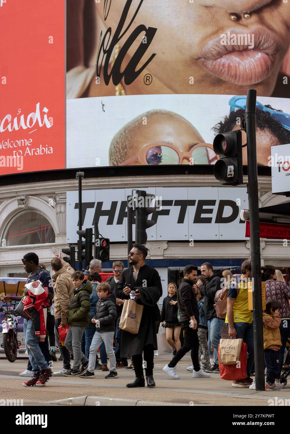 Londres, Angleterre, avril 30 2023 : les gens de Piccadilly Circus attendent de traverser la route dans une journée bien remplie avec les grands écrans derrière Banque D'Images