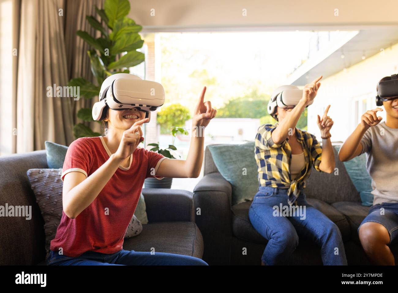 En utilisant des casques VR, des amis appréciant le jeu de réalité virtuelle dans le salon Banque D'Images