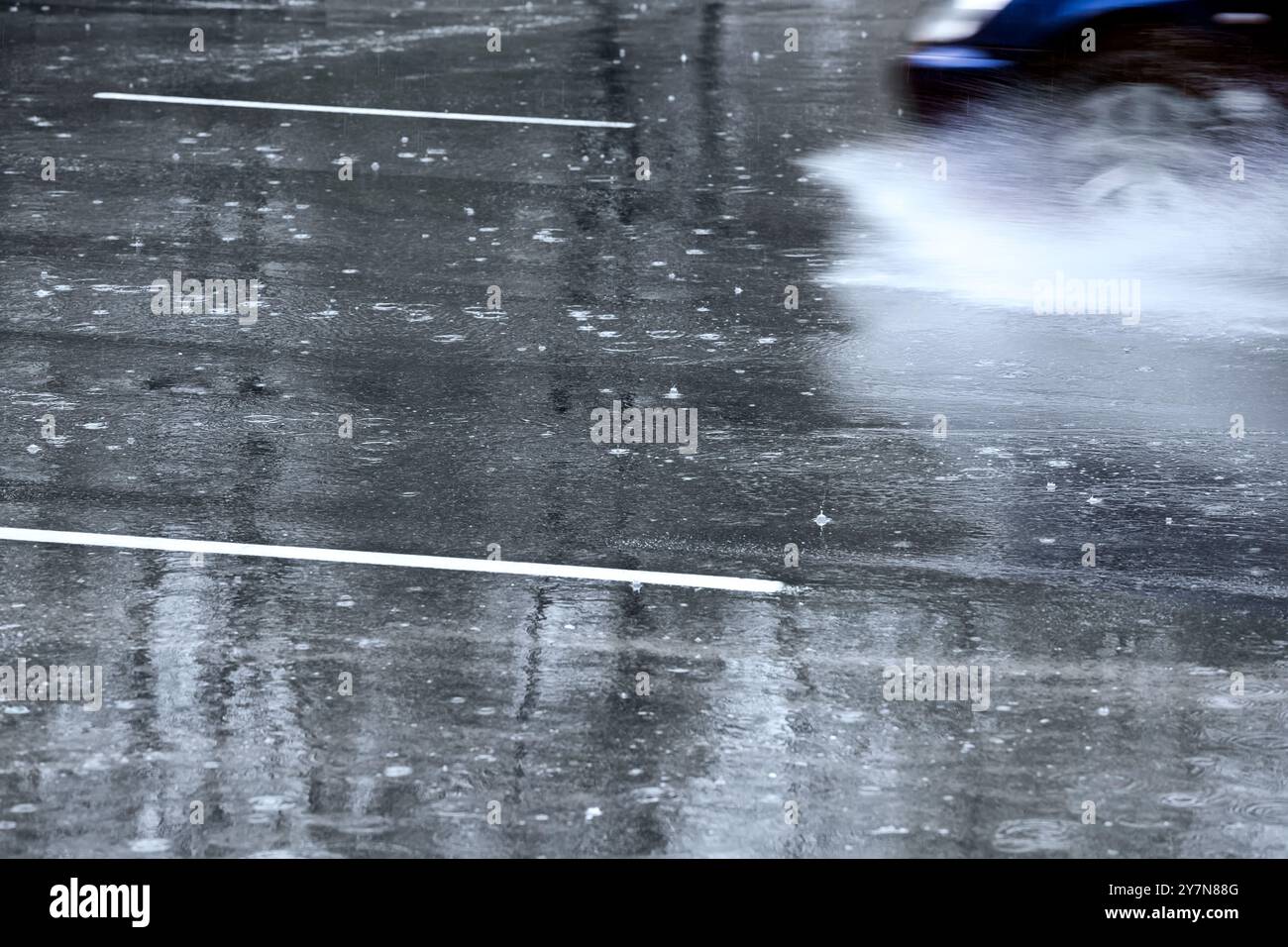 la voiture roule sur route mouillée avec de l'eau pulvérisée par les roues. Banque D'Images