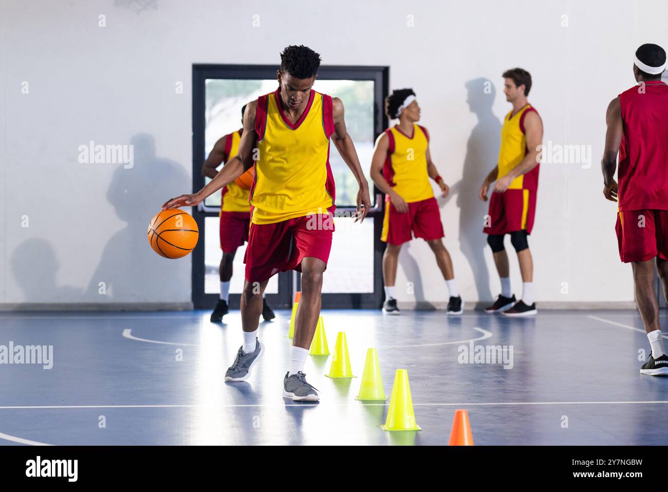 Dribble basket-ball autour des cônes, jeune athlète pratiquant des compétences dans la salle de gym Banque D'Images