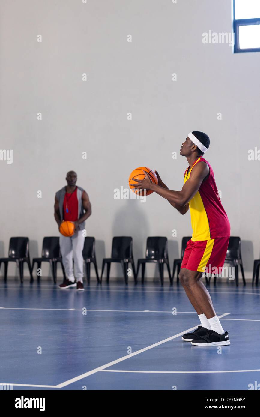 Jouer au basket-ball, athlète en uniforme rouge et jaune se préparant à tirer la balle, copier l'espace Banque D'Images