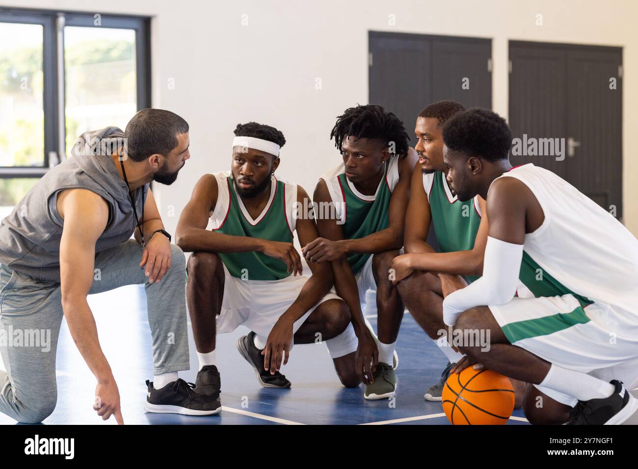 Entraîneur de basket-ball donnant une stratégie aux joueurs de l'équipe sur le terrain pendant l'entraînement Banque D'Images