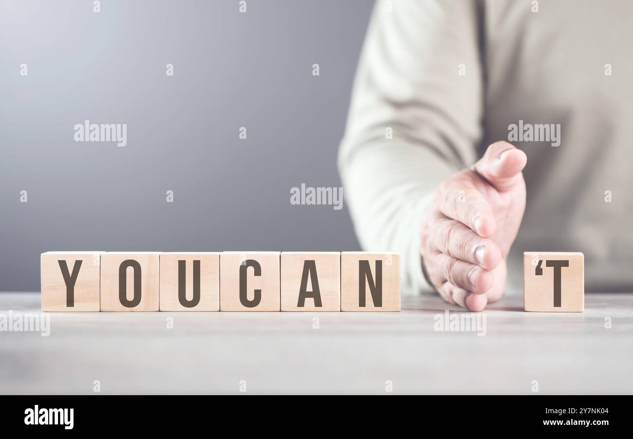 La main sépare la lettre « T » du mot « vous ne pouvez pas », la transformant en « CAN ». L'image symbolise le dépassement des obstacles, le passage du doute à Banque D'Images