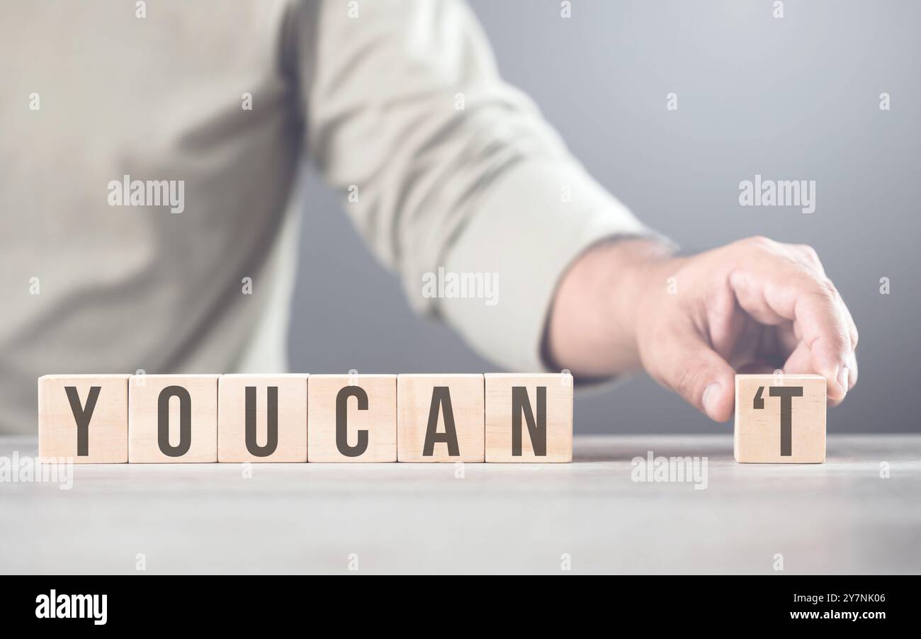 La main sépare la lettre « T » du mot « vous ne pouvez pas », la transformant en « CAN ». L'image symbolise le dépassement des obstacles, le passage du doute à Banque D'Images