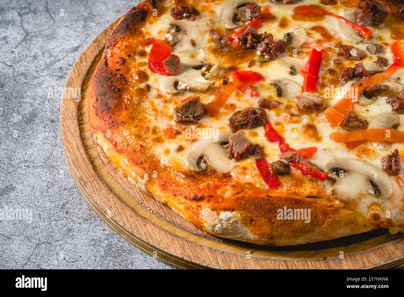Pizza avec paprika et rôti de bœuf sur planche à découper sur table en pierre Banque D'Images