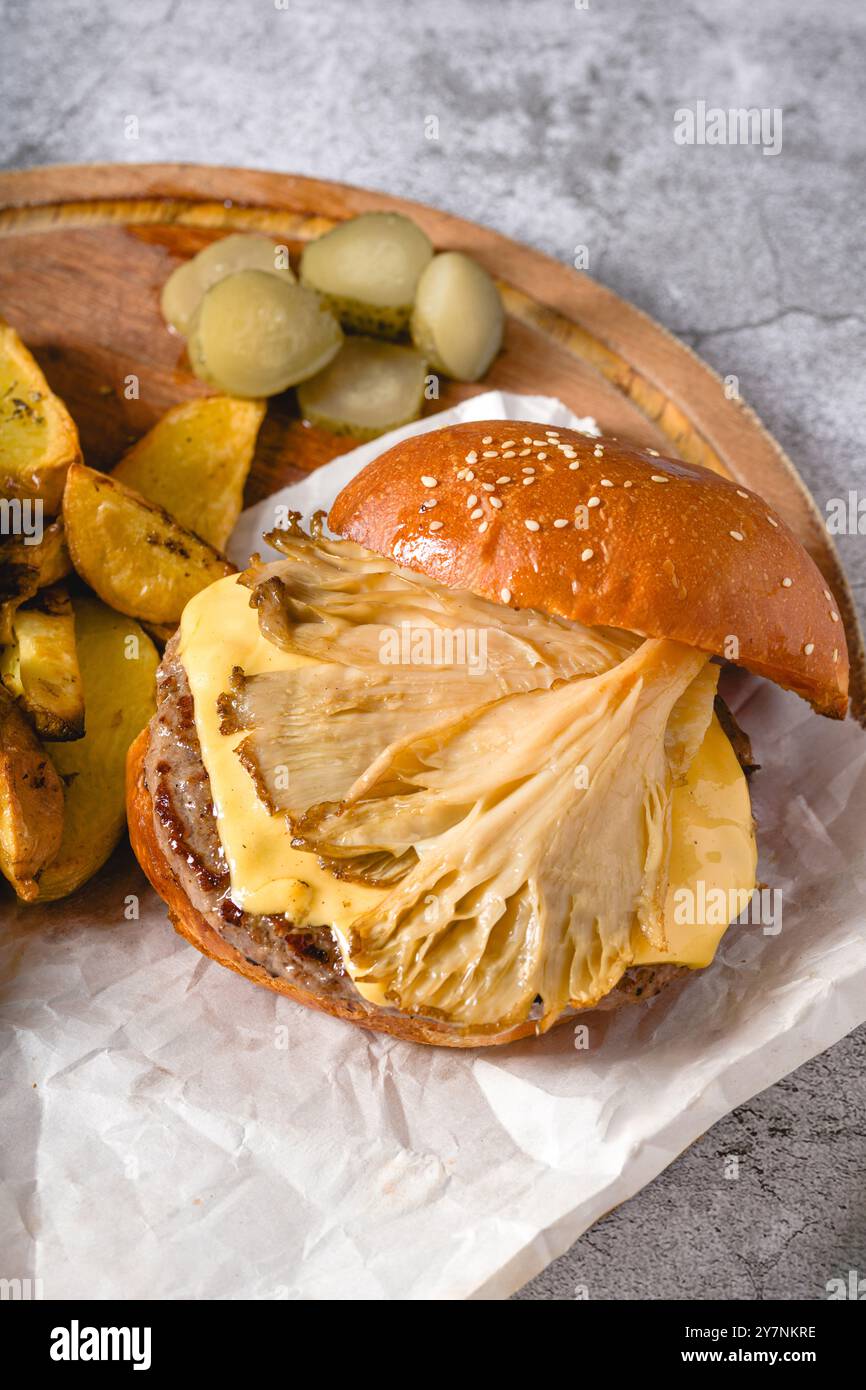 Hamburger avec des huîtres et du fromage cheddar sur une planche à découper en bois Banque D'Images