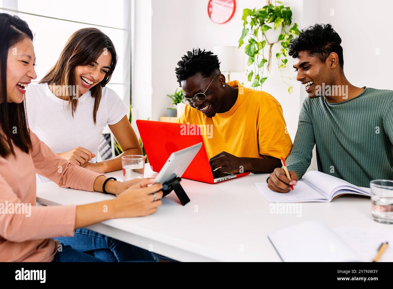 Jeune groupe d'amis étudiants heureux travaillant ensemble avec un ordinateur portable à la maison Banque D'Images