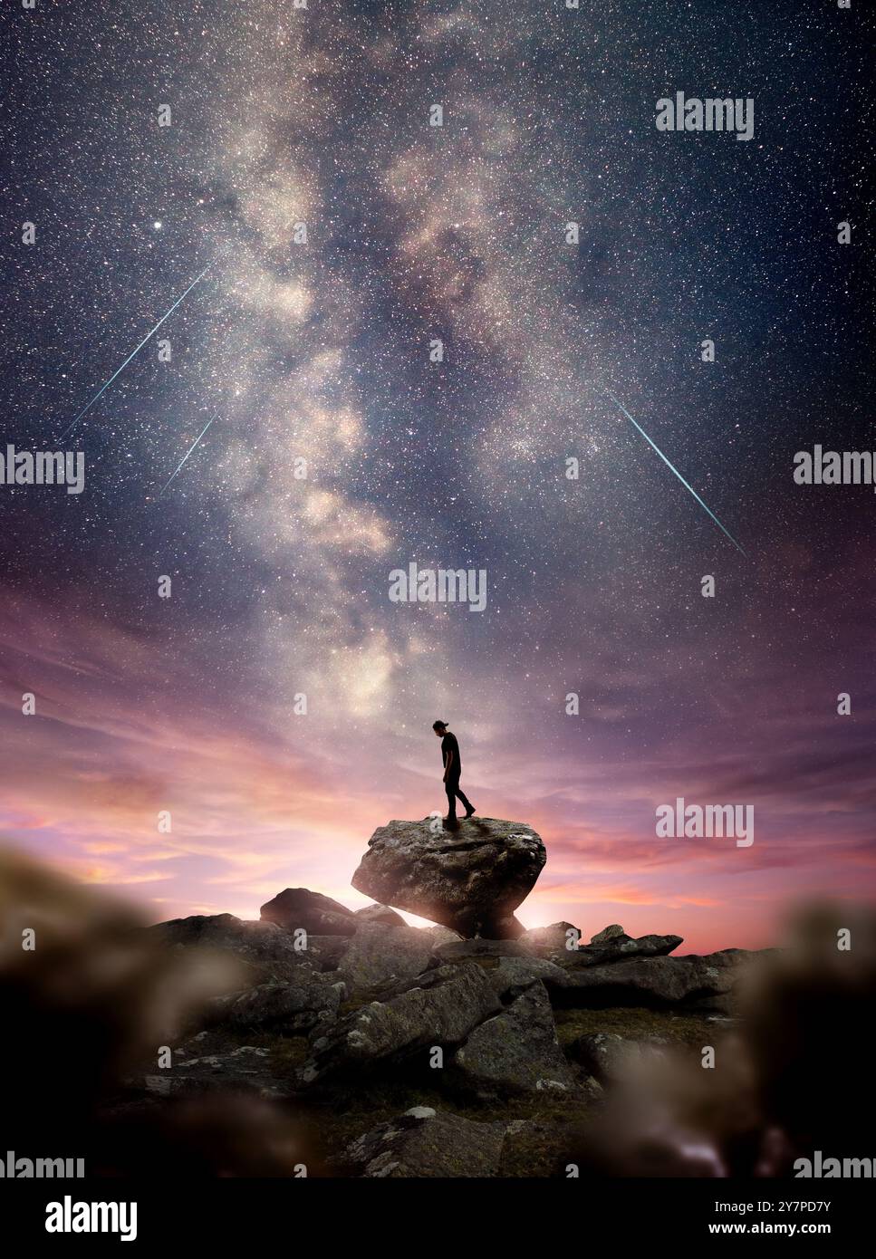 Un homme debout sur un rocher alors que la galaxie laiteuse s'élève dans le ciel nocturne au crépuscule. Photo composite Banque D'Images