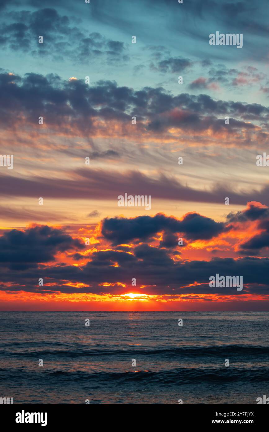 Beau paysage nuageux au-dessus de la mer, tir vertical au lever du soleil Banque D'Images