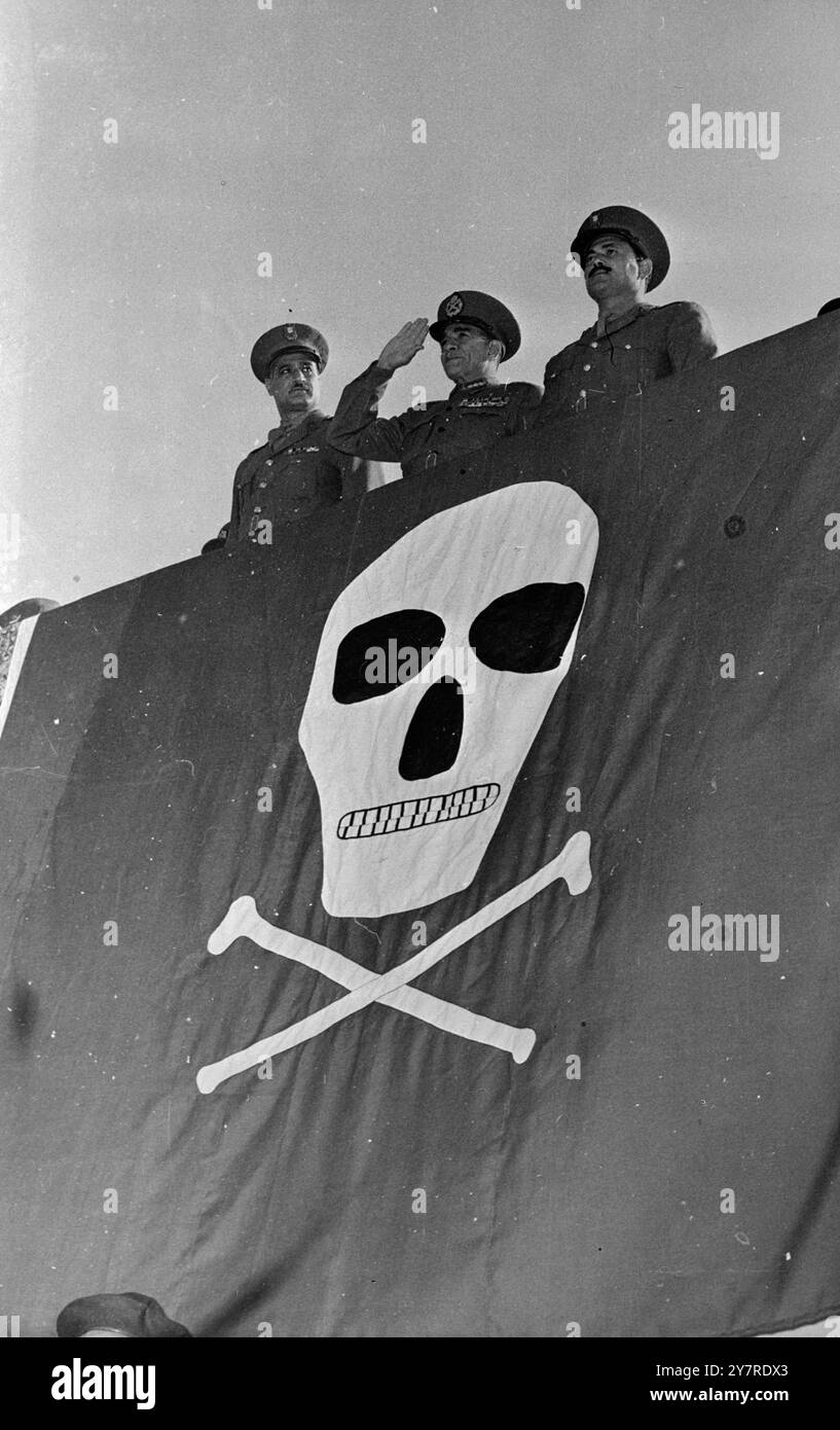 QUI EST LE PIRATE ? Négouib prend le salut sur le crâne et les os croisés. Le 23 janvier 1954 marquait le premier anniversaire de la libération en Egypte. Au Caire, le président égyptien, le général Négouib, a organisé son plus grand défilé à ce jour - de 35 000 miliciens volontaires. Parmi ceux-ci figuraient trois cents sten gun girls vêtues d'une robe de combat vert olive. Le général Négouib a pris le salut d'un stand spécialement érigé sur la place républicaine, drapé d'un énorme crâne rouge et blanc et d'os croisés. La photo de l'I.N.P. montre le général Néguib prenant le salut sur le stand spécialement érigé sur la place républicaine. 453/SP Banque D'Images