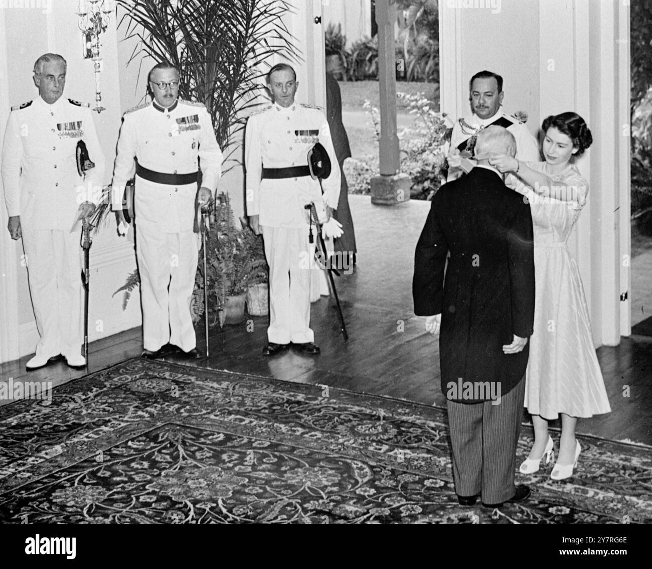 La reine détient l'investiture en Jamaïque 28.11.53. S.M. la Reine a tenu hier une investiture à King's House, Kingston, Jamaïque, au cours de laquelle elle a surnommé un chevalier et décerné des prix à 13 autres personnes. La photo de H.F.P. montre que la Reine décerne l'ordre de Commandeur de l'Empire britannique au colonel A.G. Curphey, M.C. et E.D. en arrière-plan se trouvent, de gauche à droite : le commodore K. MacNeal Campbell Walter, R.N. ; le brigadier Cosby Jackson, commandant de la région des Caraïbes ; le lieutenant-colonel D.J. Atkinson, de l'état-major du brigadier ; le commissaire adjoint de la police jamaïcaine Noel Crosswell. PJ/72924 publié par Internati Banque D'Images