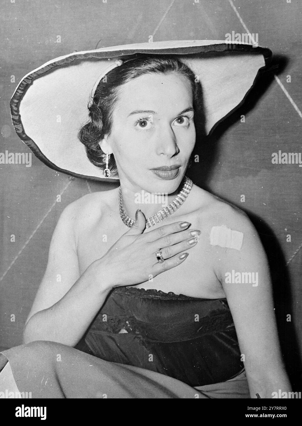 TENTATIVE DE MEURTRE SUR LA DANSEUSE DE FAROUK 4,8.53Une tentative de MEURTRE sur la vie de Dawlath Soliman, la danseuse préférée de l'ex-roi Farouk, a été faite dimanche soir au Bongo Bar de Munich où elle se produit. Comme elle a reconnu les applaudissements à la fin de son acte, un inconnu a tiré un seul coup de feu, qui l'a frappée à l'épaule, et s'est échappé en moto. La photo montre Dawlath Soliman indique le pansement collant qui recouvre la blessure par balle dans son épaule. 4 août 1953 Banque D'Images