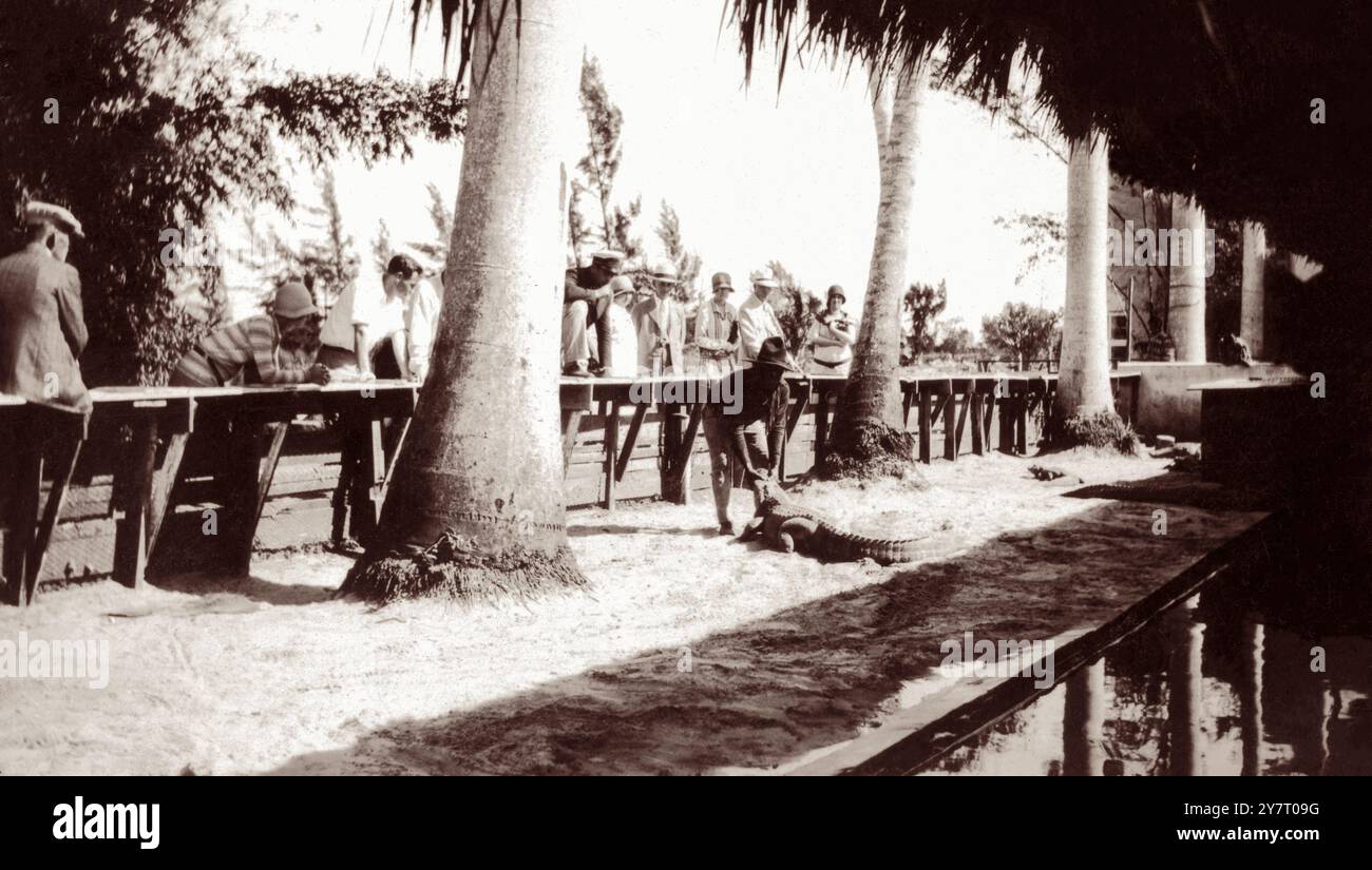 Une petite foule regarde un Indien Séminole lutter contre un alligator au Musa Isle Seminole Indian Village à Miami, en Floride, au début du XXe siècle. (ÉTATS-UNIS) Banque D'Images