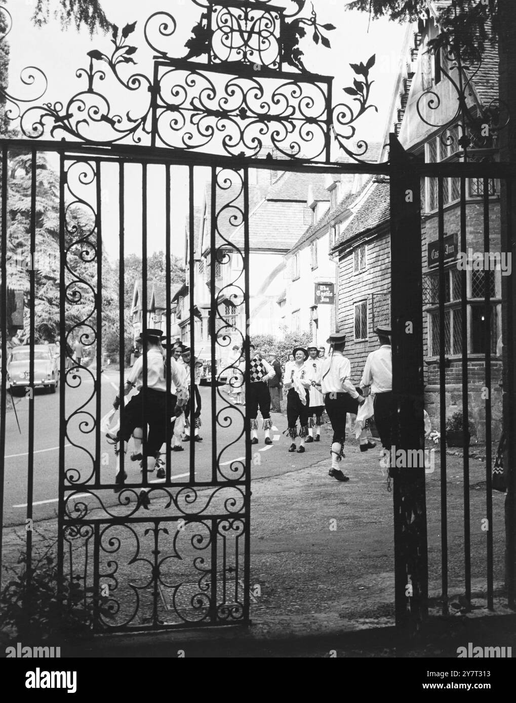 Les danseurs Morris dans le village de Chiddingstone, Kent, Angleterre, Royaume-Uni, dansent devant le Castle Inn, vu à travers la porte ornée menant au château de Chiddingstone. - - 10 juillet 1960 Banque D'Images