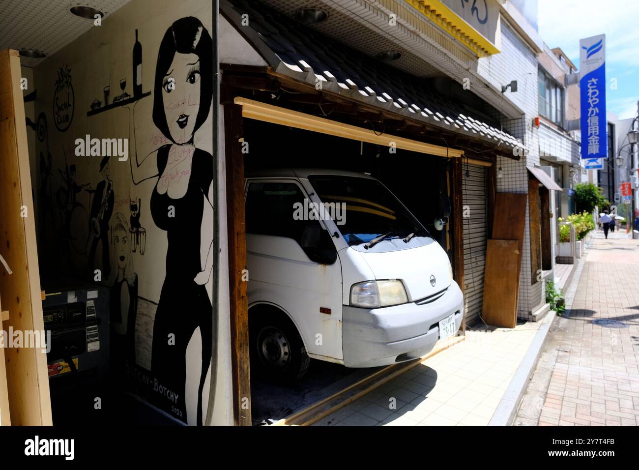 Un parking minifourgonnette dans un petit garage d'un restaurant avec une fresque d'une serveuse sur mur extérieur.Kagurazaka.Shinjuku.Tokyo.Japan Banque D'Images