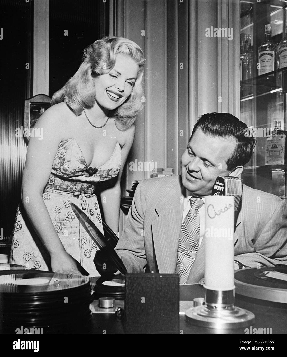 FAN DE DISQUES 26 mai 1950 intéressée par les disques, et ravie par ce qu'elle entend, l'actrice Cleo Moore, qui va dans les coulisses pour une conversation avec le disc-jockey américain Johnny Grant. Miss Moore a joué avec Gary Cooper dans Bright Leaf. Grant est disc-jockey pour Ciro's of Hollywood, où cette photo est prise. Banque D'Images