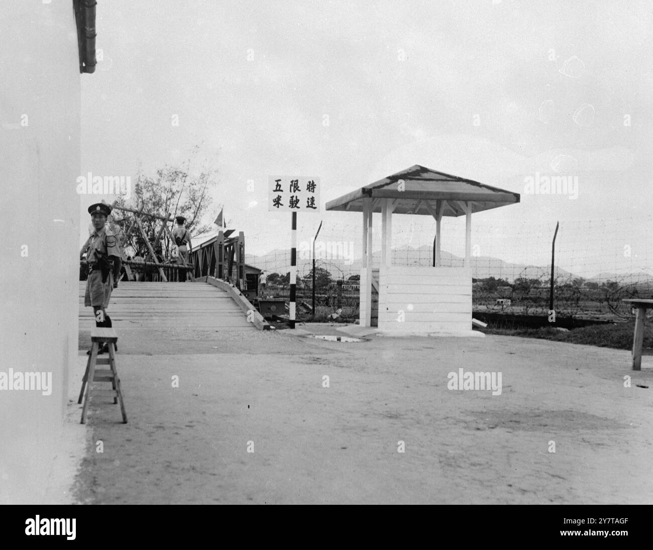 GARDE EN SERVICE 12 mai 1950 de nouvelles réglementations de contrôle de l'immigration sont maintenant appliquées à la frontière entre le territoire britannique et le territoire chinois dans la région de Hong Kong. Les règlements sont conçus pour empêcher les «indésirables» de traverser à Hong Kong. Les officiers britanniques autorisent cependant un petit trafic normal, soumis uniquement à l'inspection douanière. Depuis l'entrée en vigueur du règlement, les femmes portant des armes à feu ont été refoulées. La photo montre : un garde armé attend à un point de contrôle frontalier pendant une période de relâche Banque D'Images