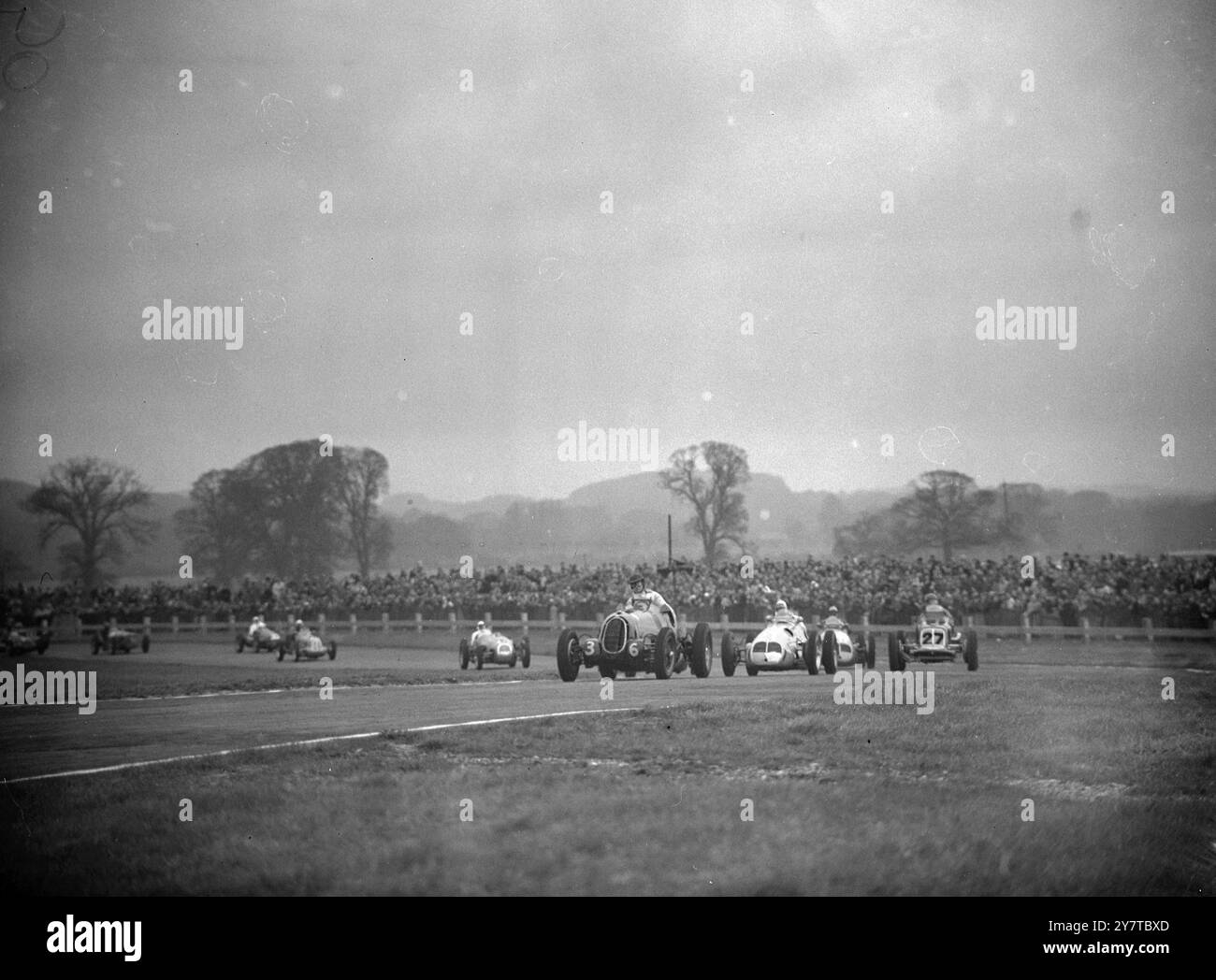 VIRAGE DANS LA COURSE DE LA COUPE CHICHESTER 11 avril 1950 les voitures sont groupées à Madgwick Corner pendant les cinq tours de course de la coupe Chichester lors de la réunion d'ouverture de la saison de course automobile sur le circuit de Goodwood près de Chichester, Sussex. En tête est R d Poore, au volant d'une Alfa Romeo suralimentée (36) Poore a pris la troisième place devant Prince Bira au volant d'une Maserati suralimentée. Prince Bira a gagné par 4,6 secondes à une vitesse de 80,63 miles à l'heure. Malgré un coup de vent, le parcours était bondé. Banque D'Images
