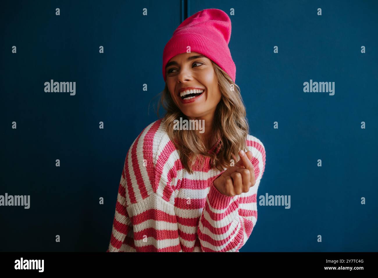 Jeune femme blonde à la mode dans les doigts claquant l'usure décontractée et souriant sur fond bleu Banque D'Images