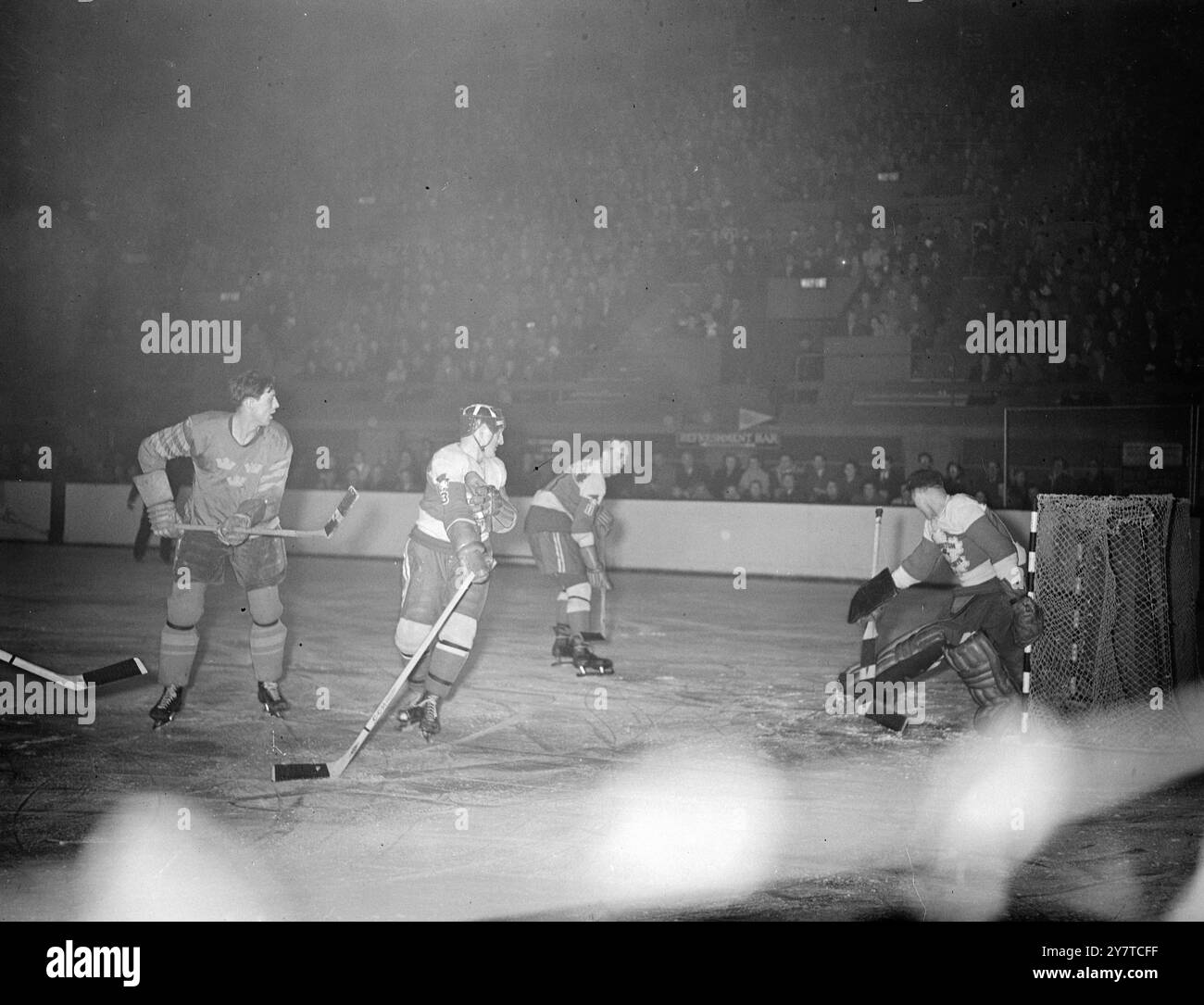 LES CHAMPIONNATS DU MONDE DU CANADA COMBATTENT LA SUÈDE ATTAQUE le gardien de but du Canada Wilbur Delaney fait une sauvegarde sensationnelle alors qu'il bloque la rondelle lors d'une attaque de l'un des membres de l'équipe de Suède (à gauche). Deux Canadiens se sont précipités pour regarder l'action : le défenseur Jim Kilburn (deuxième à partir de la gauche) et l'ailier droit M. Darling, capitaine de l'équipe canadienne (nouveau gardien de but). Le match se joue à la piscine Empire, Wembley, Londres, ce soir dans les séries du championnat mondial et européen de hockey sur glace. Le Canada a remporté le championnat. 22 mars 1950 Banque D'Images