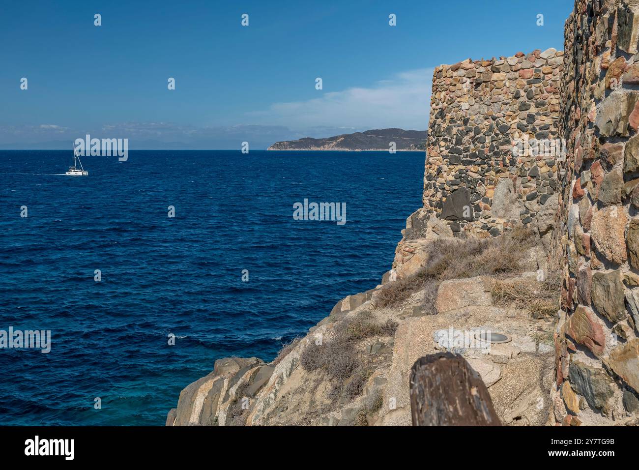 Un catamaran blanc navigue près de la Fortezza Vecchia à Villasimius, Sardaigne, Italie Banque D'Images