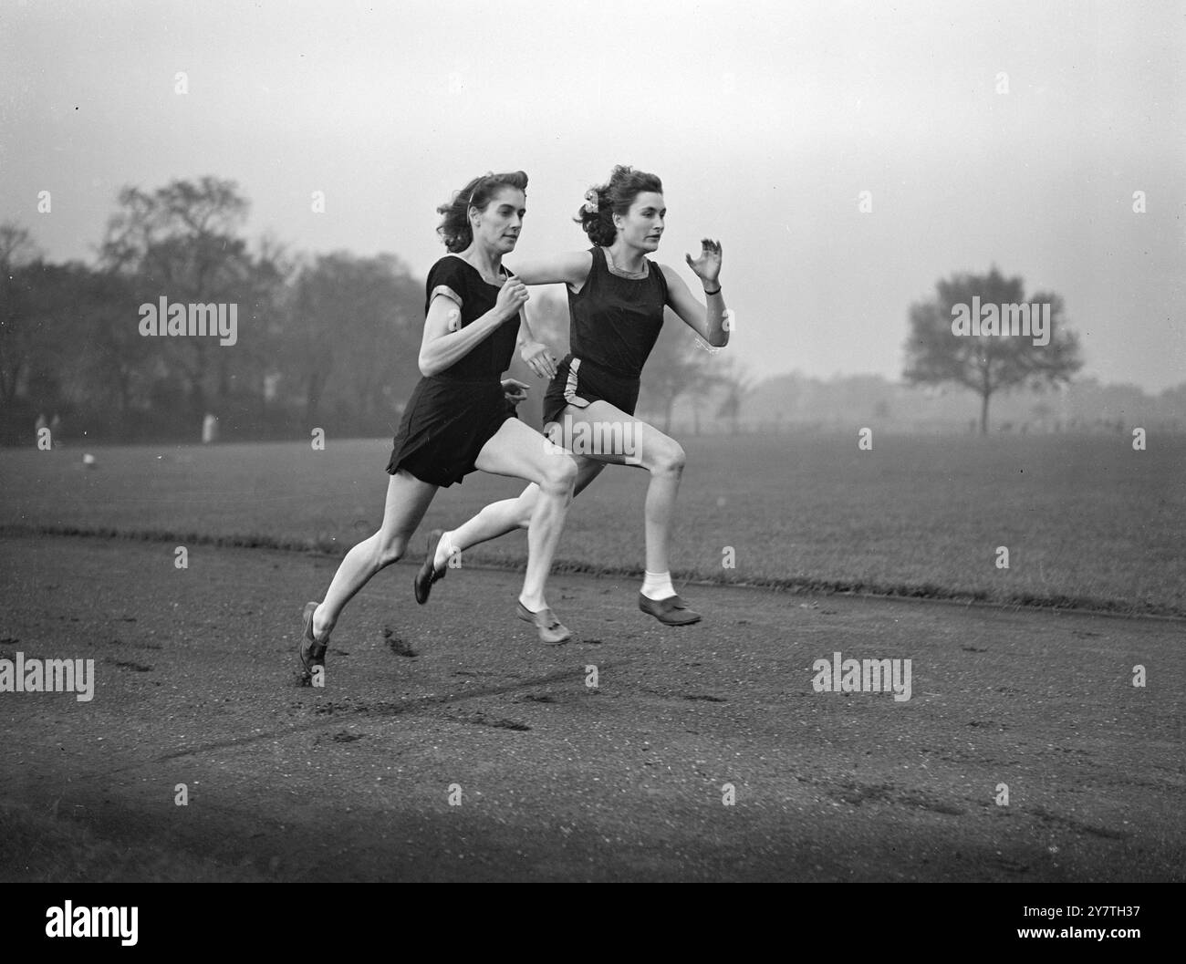 EMMENANT LA MOITIÉ DU MONDE DANS LEUR FOULÉE en prévision des Jeux de l'Empire en Nouvelle-Zélande en février prochain Dorothy Manley (Essex) -à gauche- et le champion des haies Jean Desforges (Essex) alors qu'ils sautent sur la piste à Victoria Park, Londres. Les deux sont parmi les six athlètes qui formeront l'équipe féminine britannique aux jeux Miss Manley (MRS Peter Hall, dans la vie privée, a été finaliste face à Fanny Blankers-Koen, de Hollande, au 100 mètres des Jeux Olympiques de 1948. 31 OCTOBRE 1949 Banque D'Images